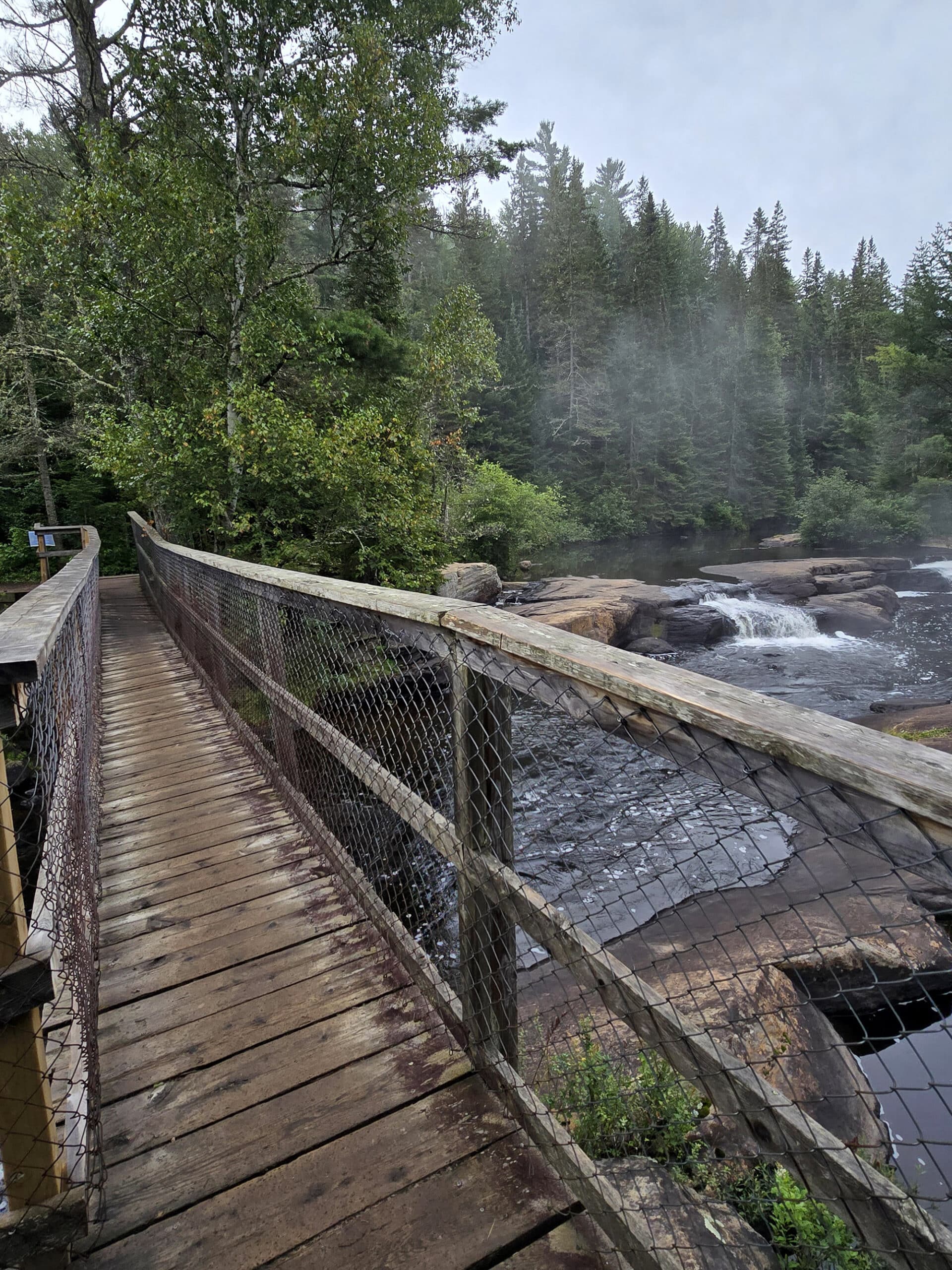 A wonky wooden bridge crossing the madawaska river.