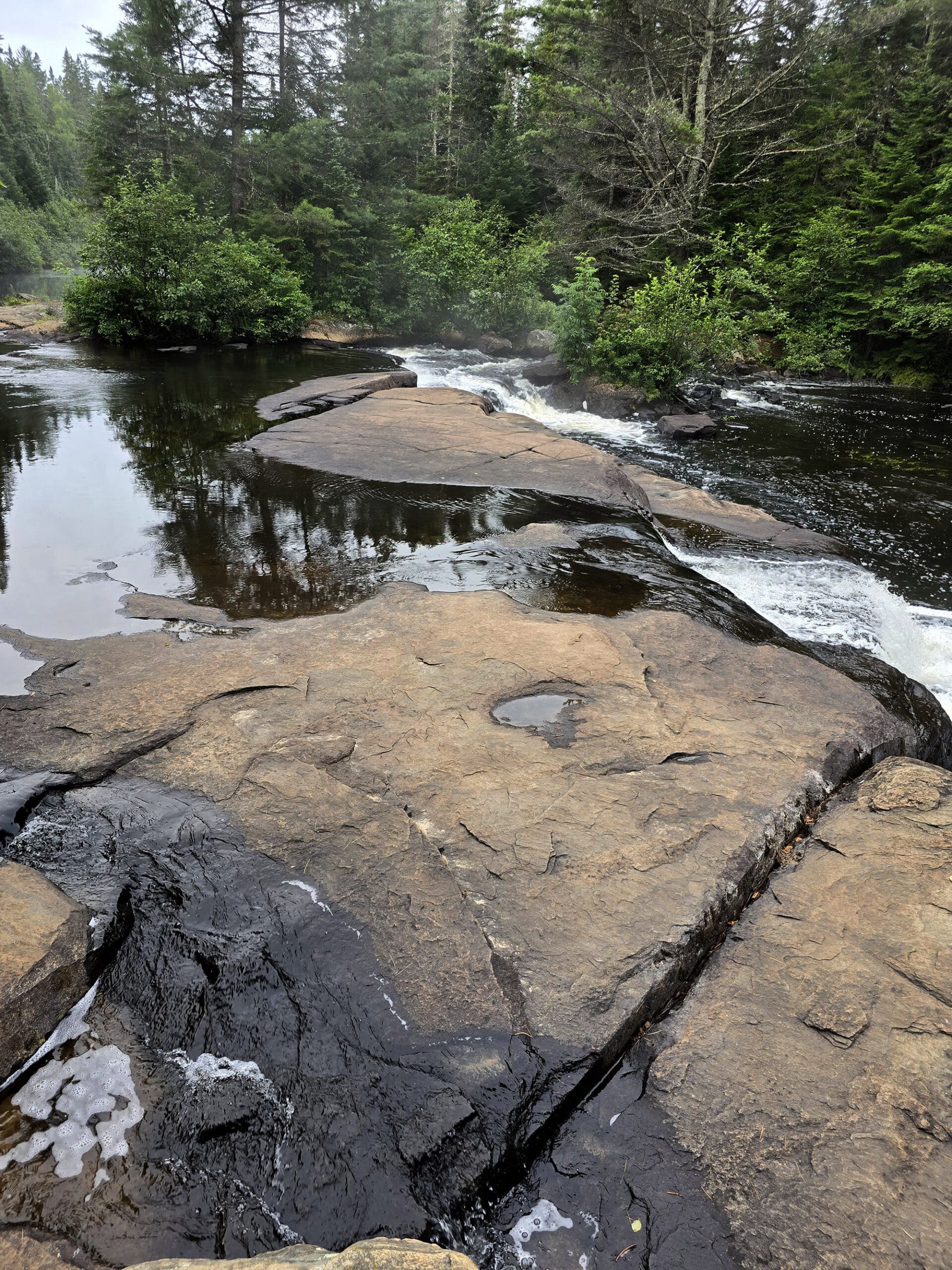 A series of flat rocks overlooking the top of Provoking Falls.