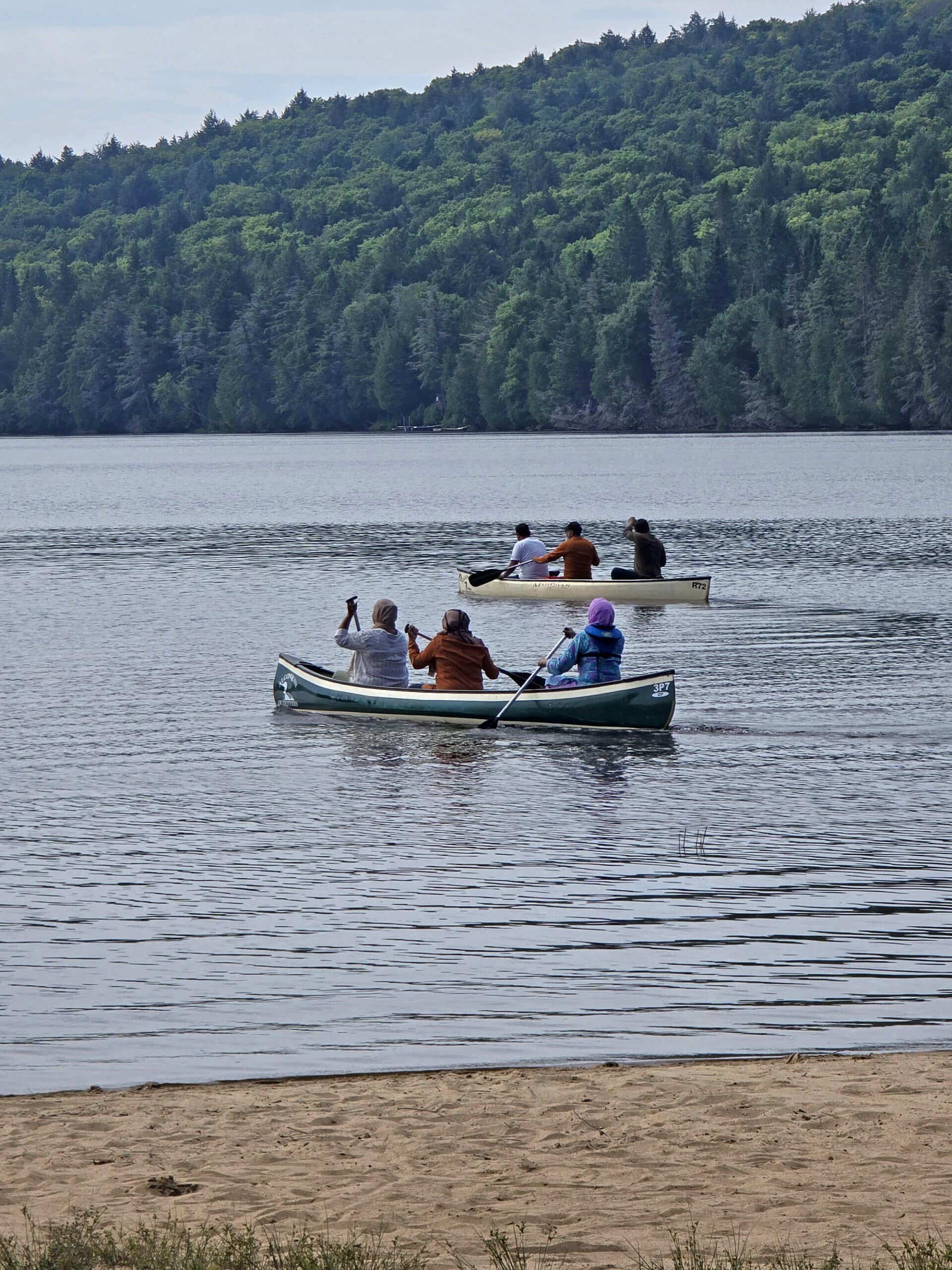 2 canoes full of people paddling on rock lake.