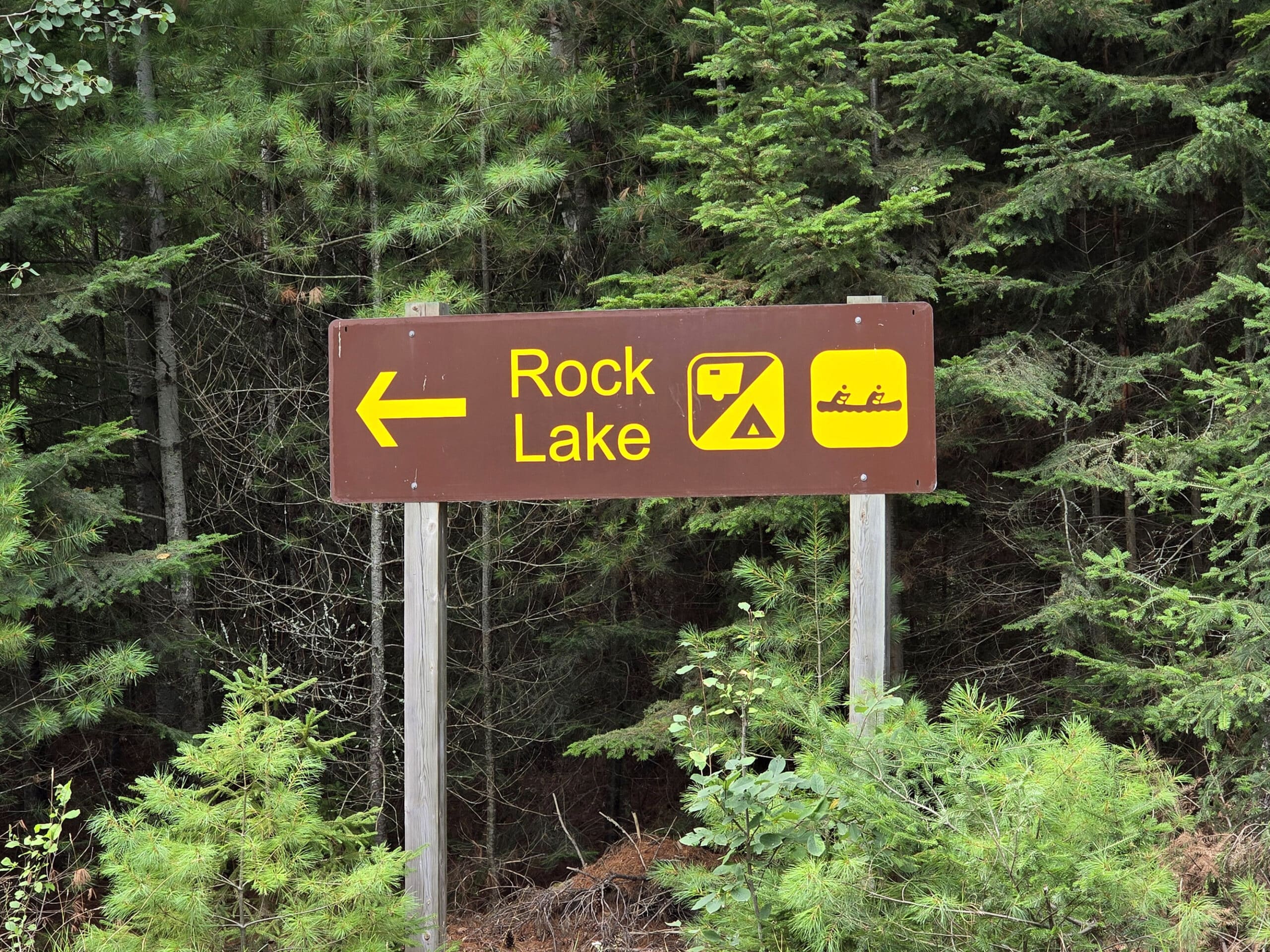 A brown and white campground sign pointing to rock lake.