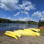 Several yellow canoes on the shore of tea lake.