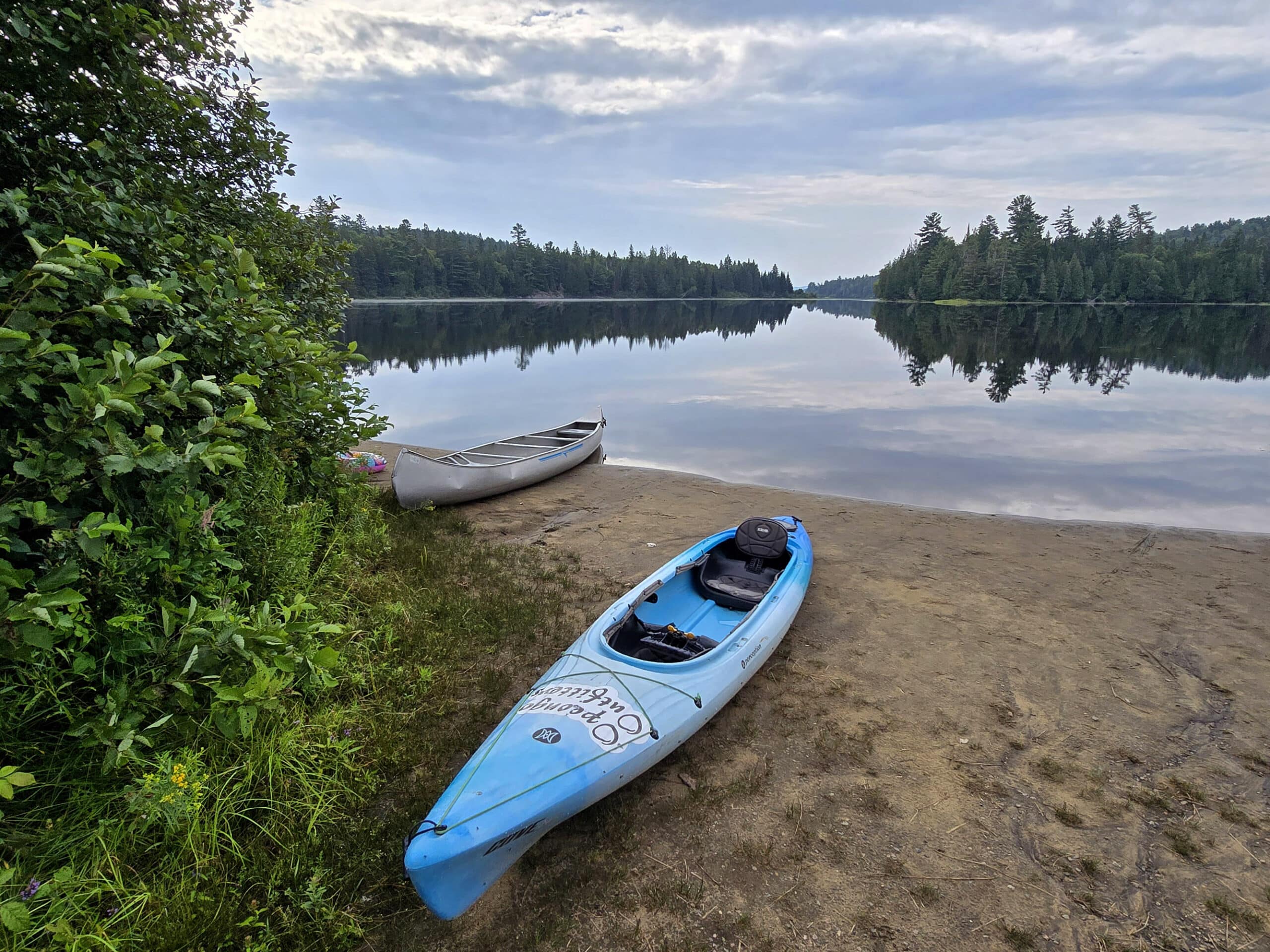 A blue kayak on the beach at Whitefish Lake campground.