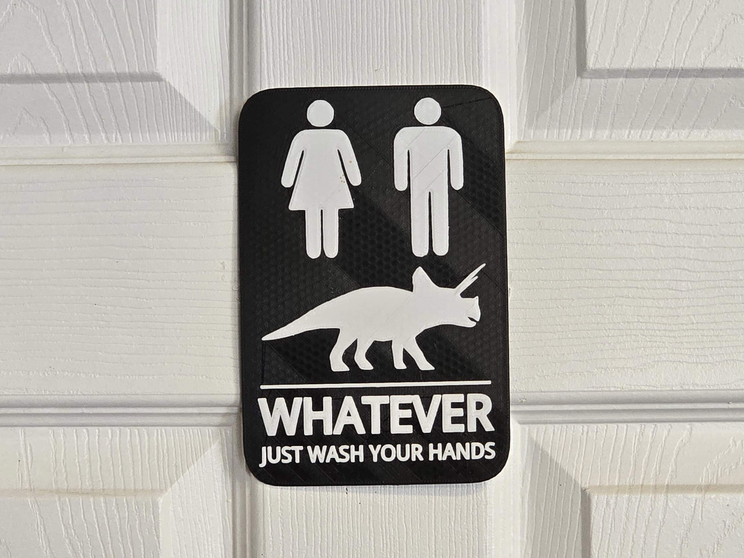 a washroom sign with male, female, and dinosaur symbols. Text says whatever just wash your hands.