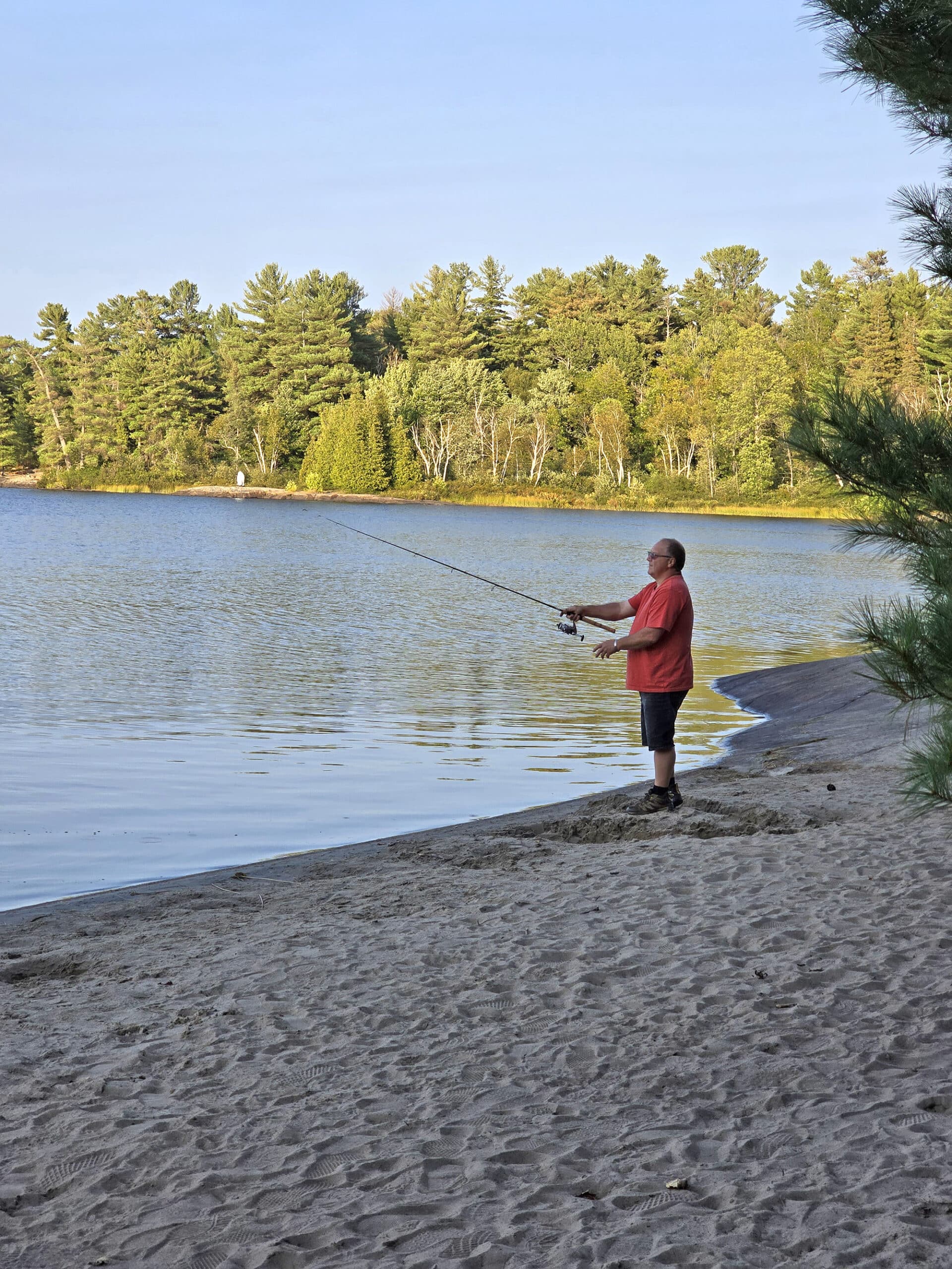 A man fishing from a beach.