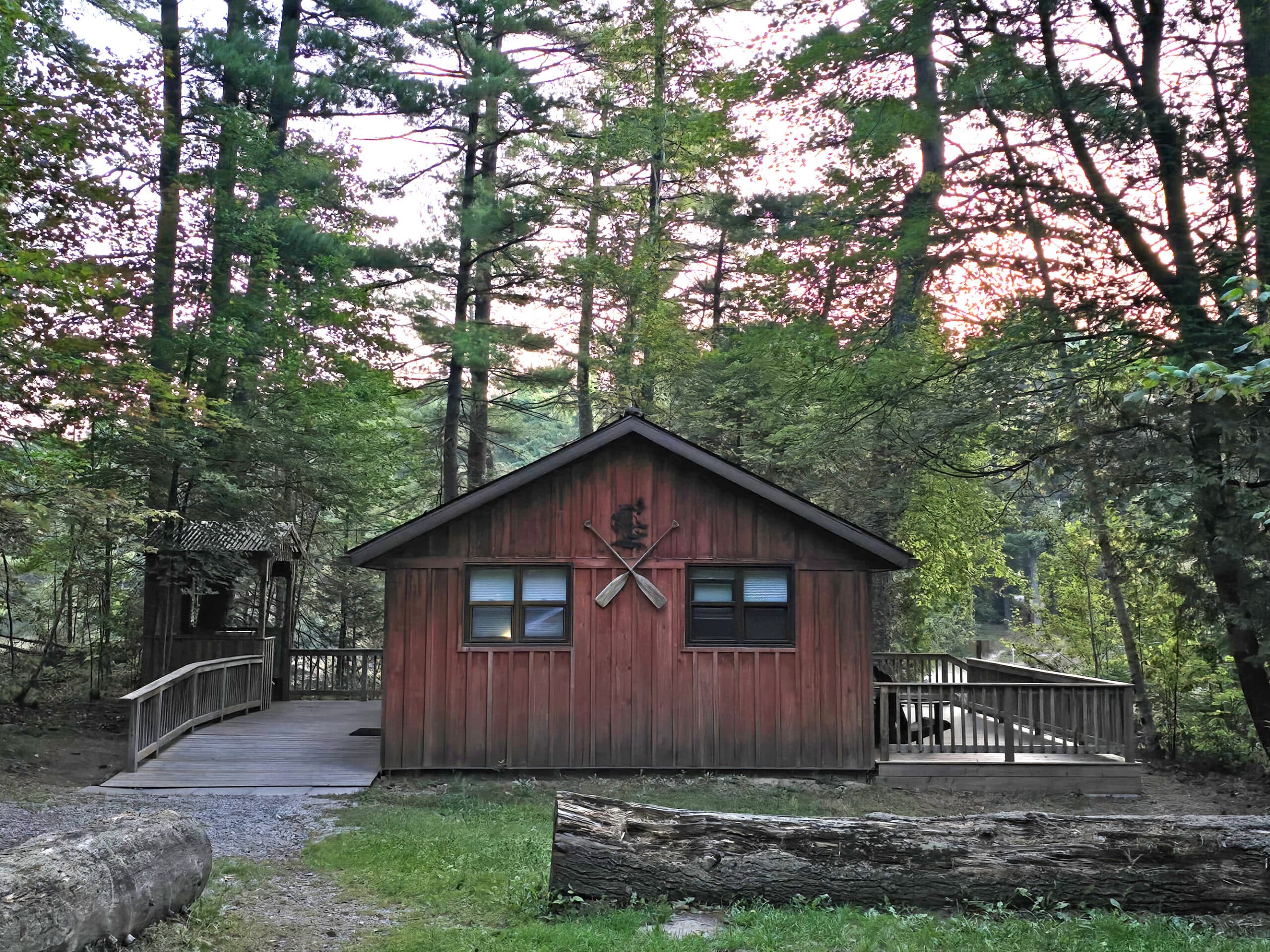 A rustic cabin with a lake behind it.