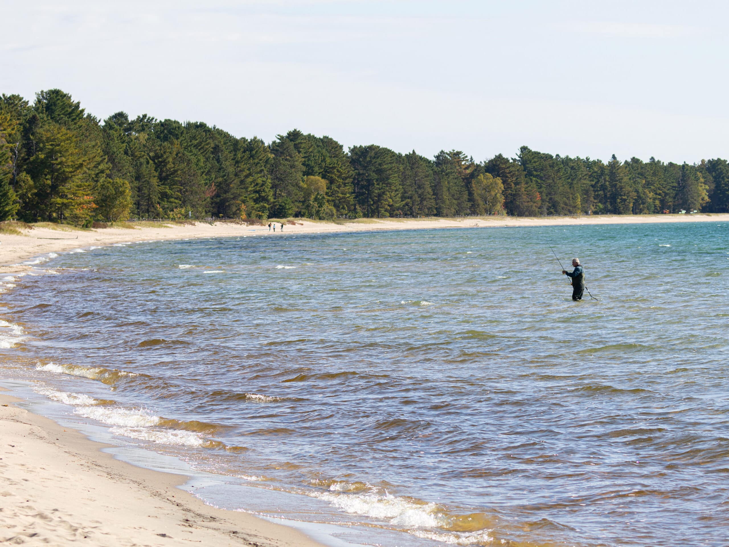 A man standing up in Pancake Bay, fishing.