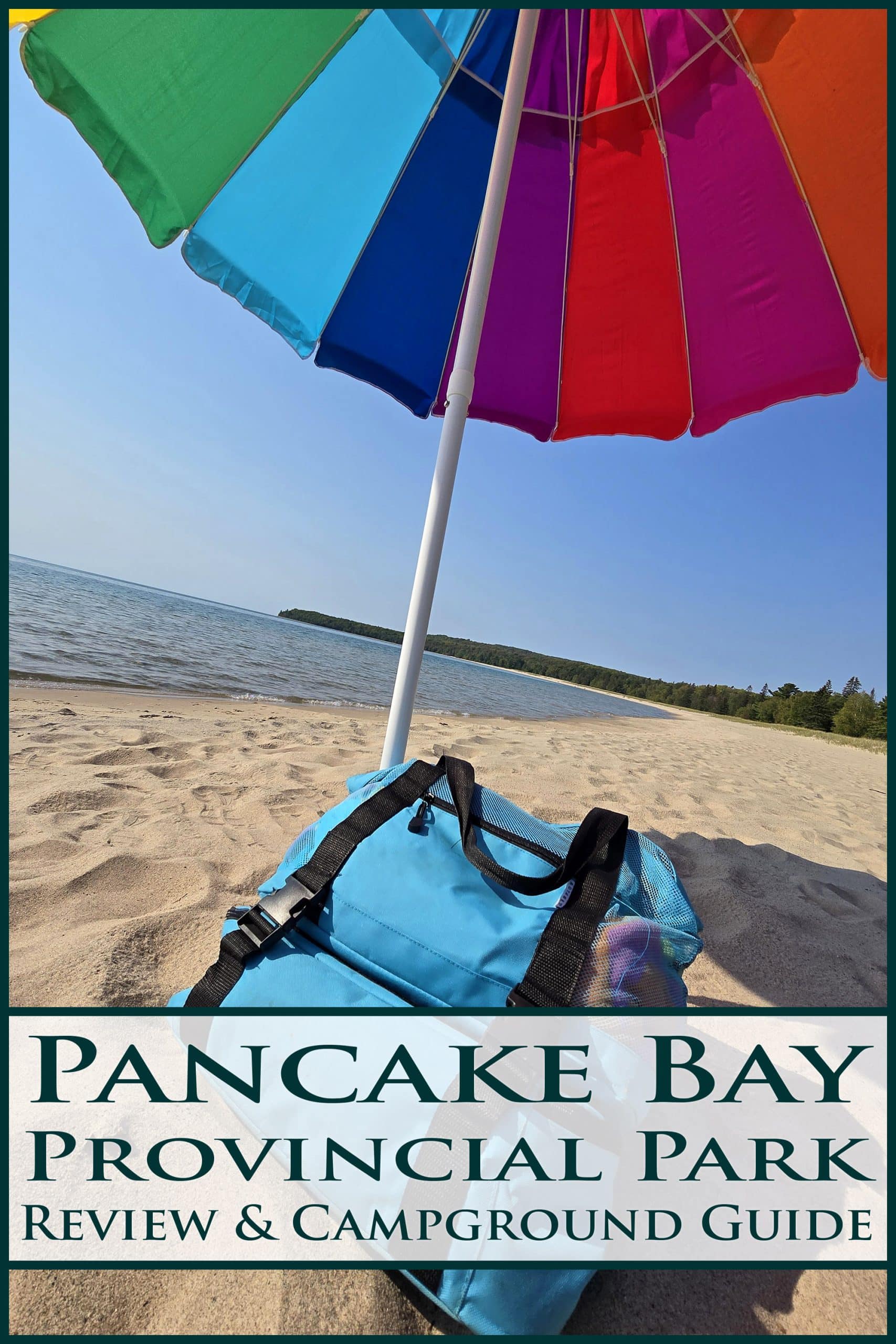 A beach back and rainbow umbrella on a pale sand beach. Overlaid text says pancake bay provincial park review and camping guide.