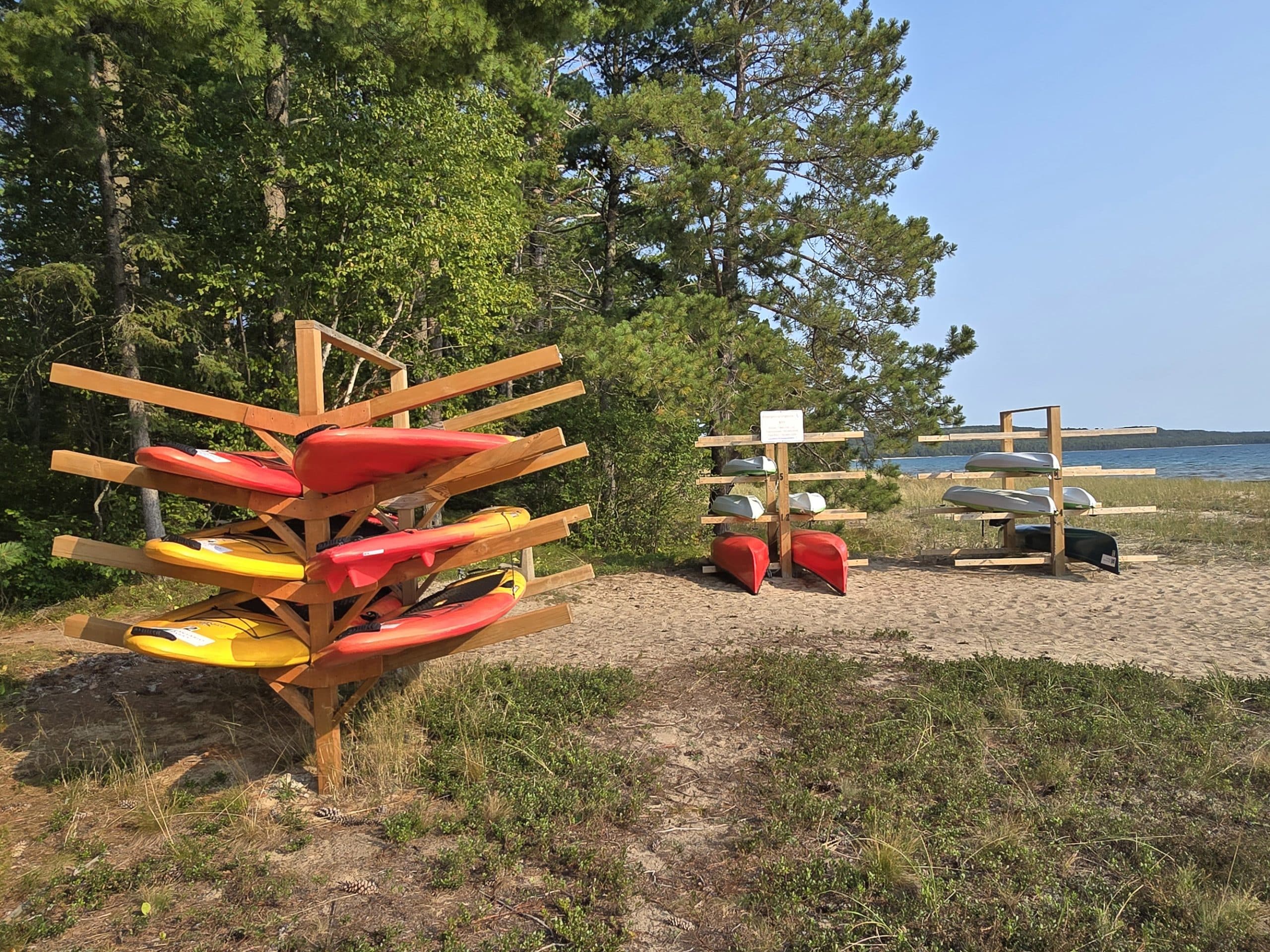 2 racks of canoes, kayaks, and stand up paddle boards on pancake bay beach.