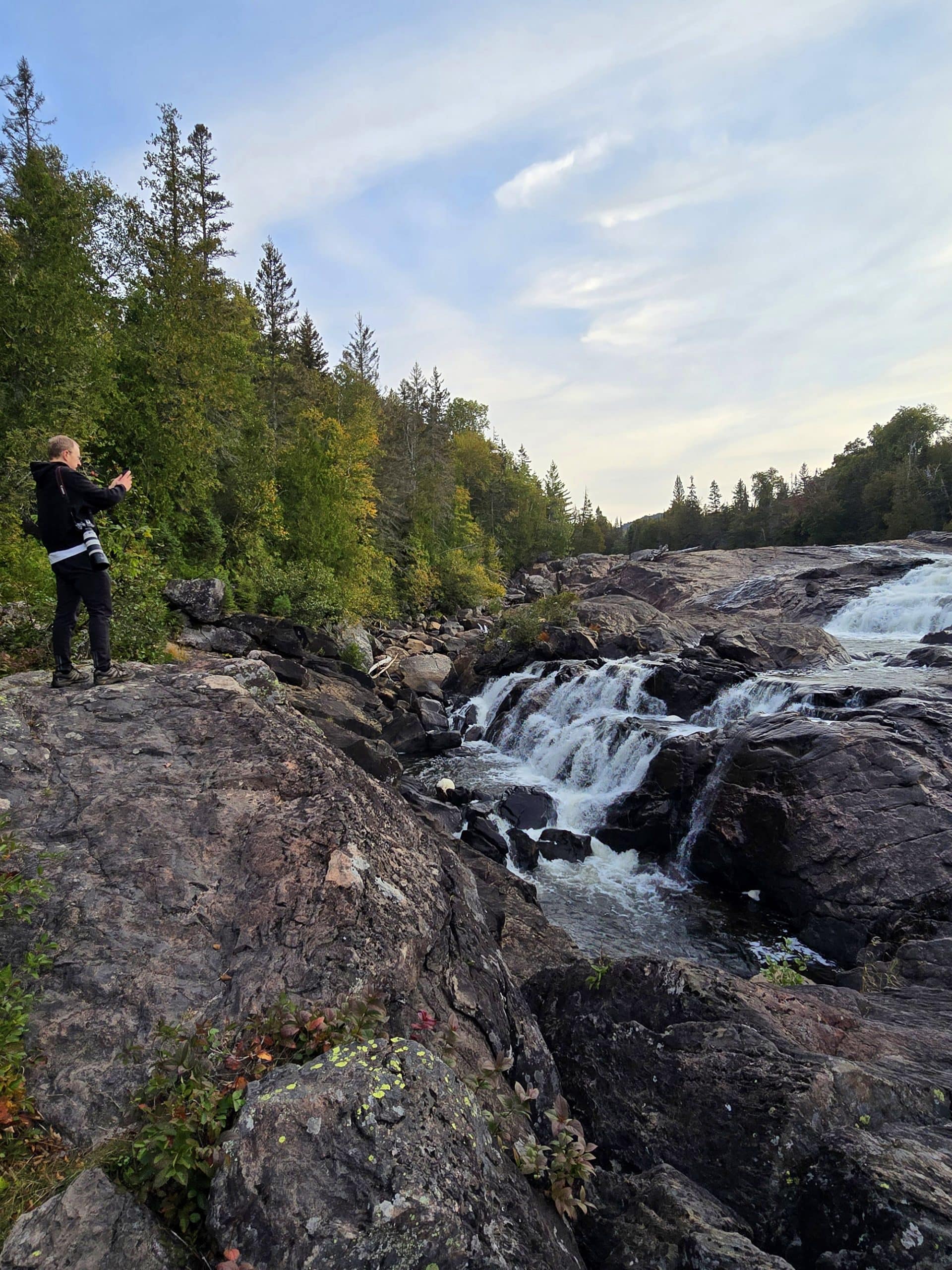 A middle aged man photographing one of the waterfalls at Sand River Falls on the Pinguisibi Trail.