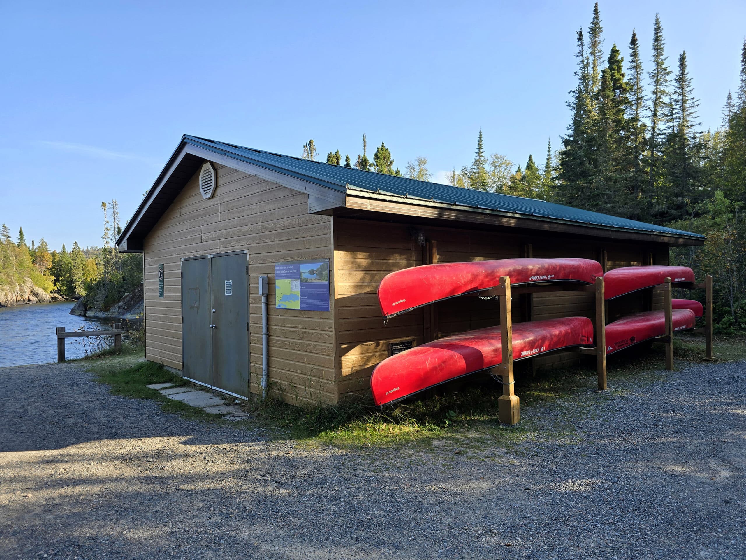 A building with a rack of red canoes in front.