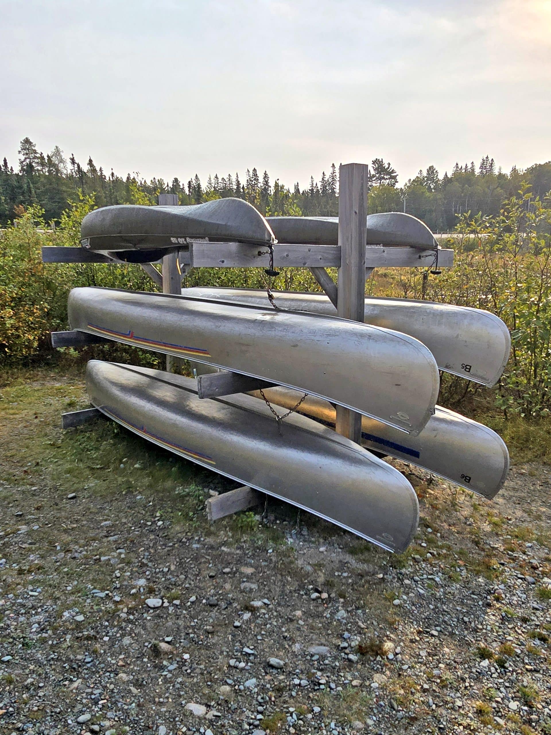 A rack of silver coloured canoes next to rabbit blanket lake.