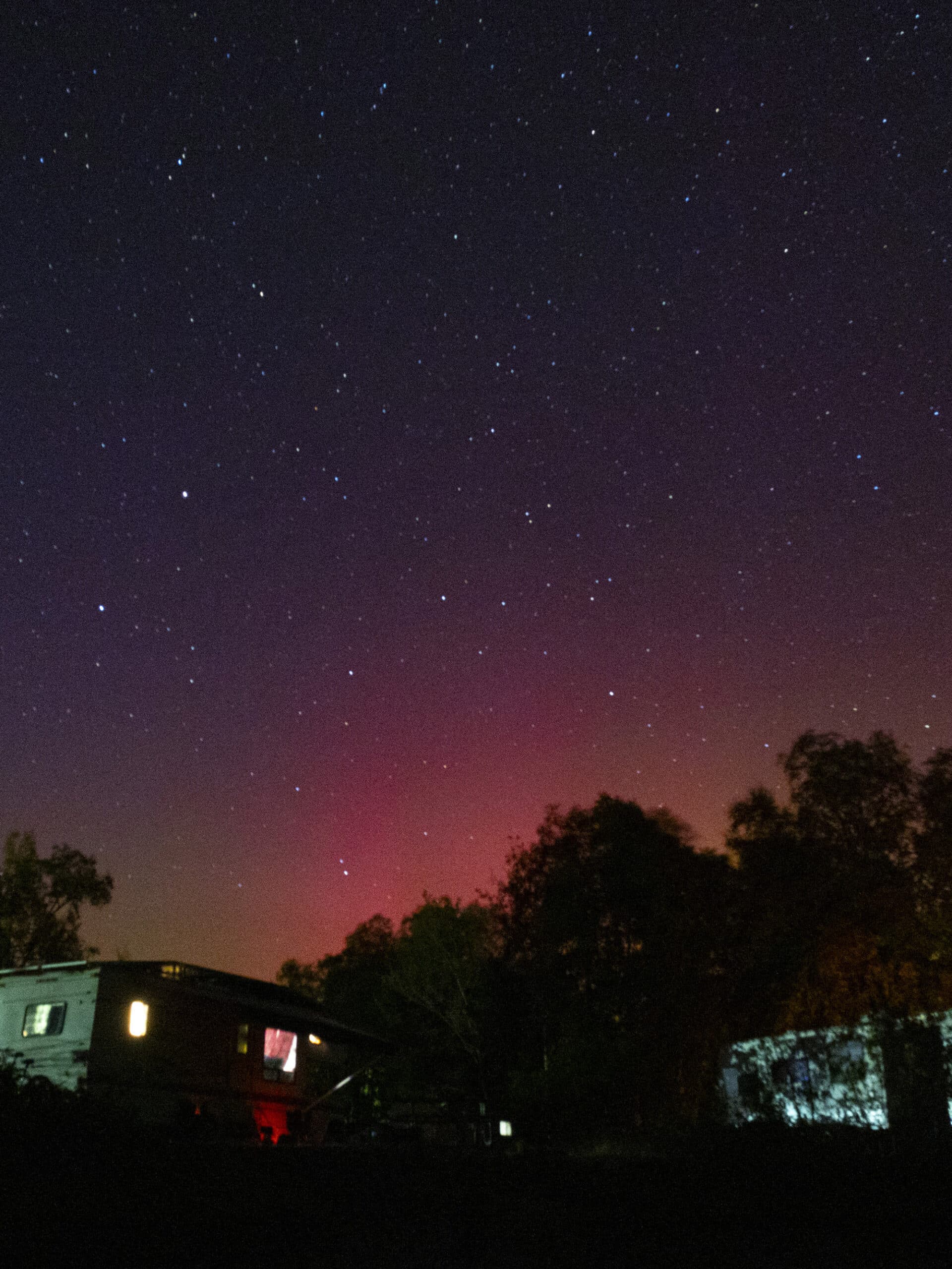 Pink and green aurora boreals over 2 RVs.