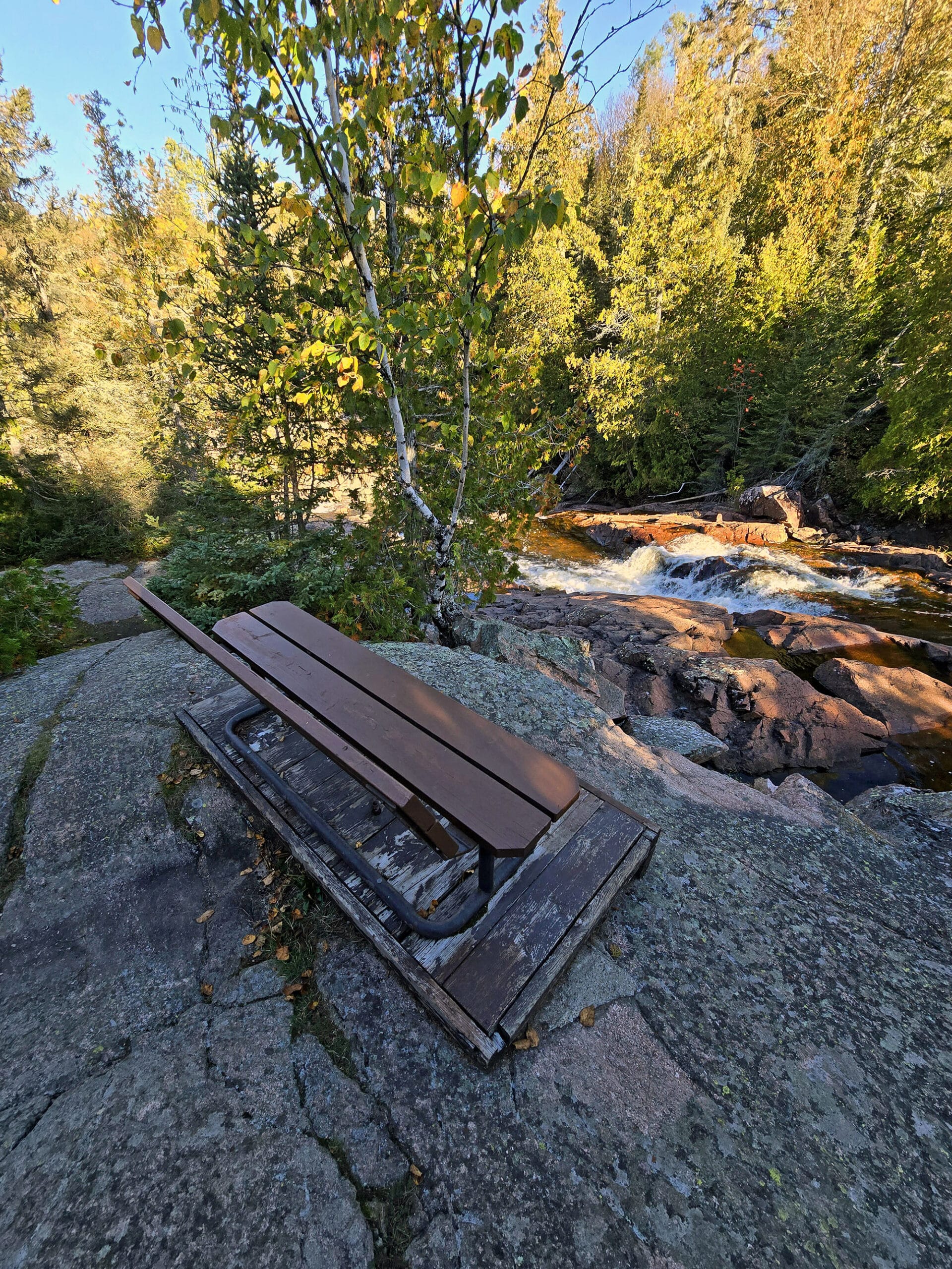 A seating bench overlooking one set of waterfalls at Rainbow Falls Provincial Park.