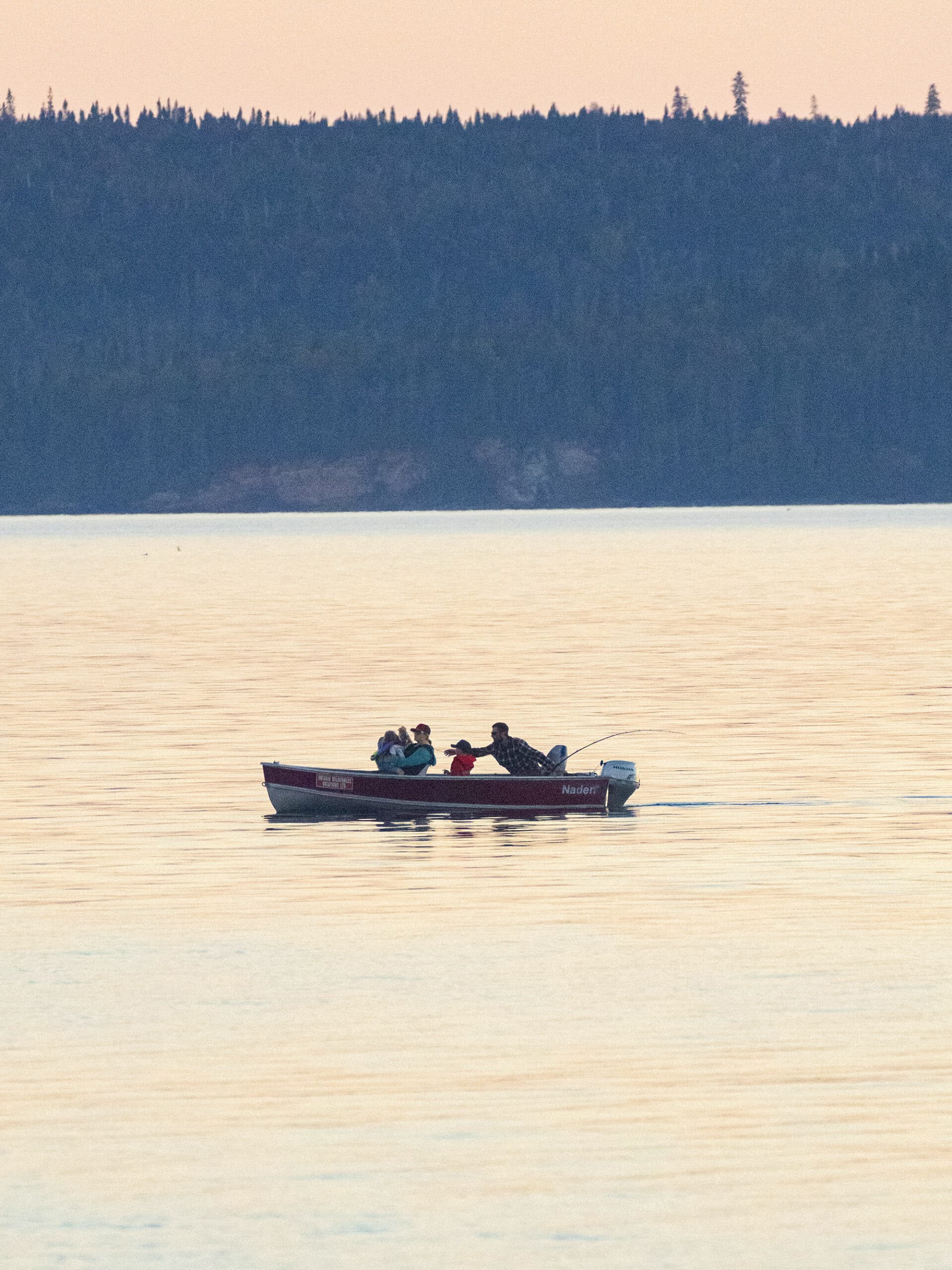 A family fishing on a small boat on lake superior.