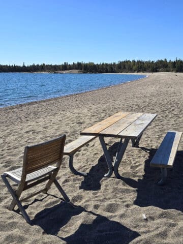 A picnic table and chair on a rocky beach.