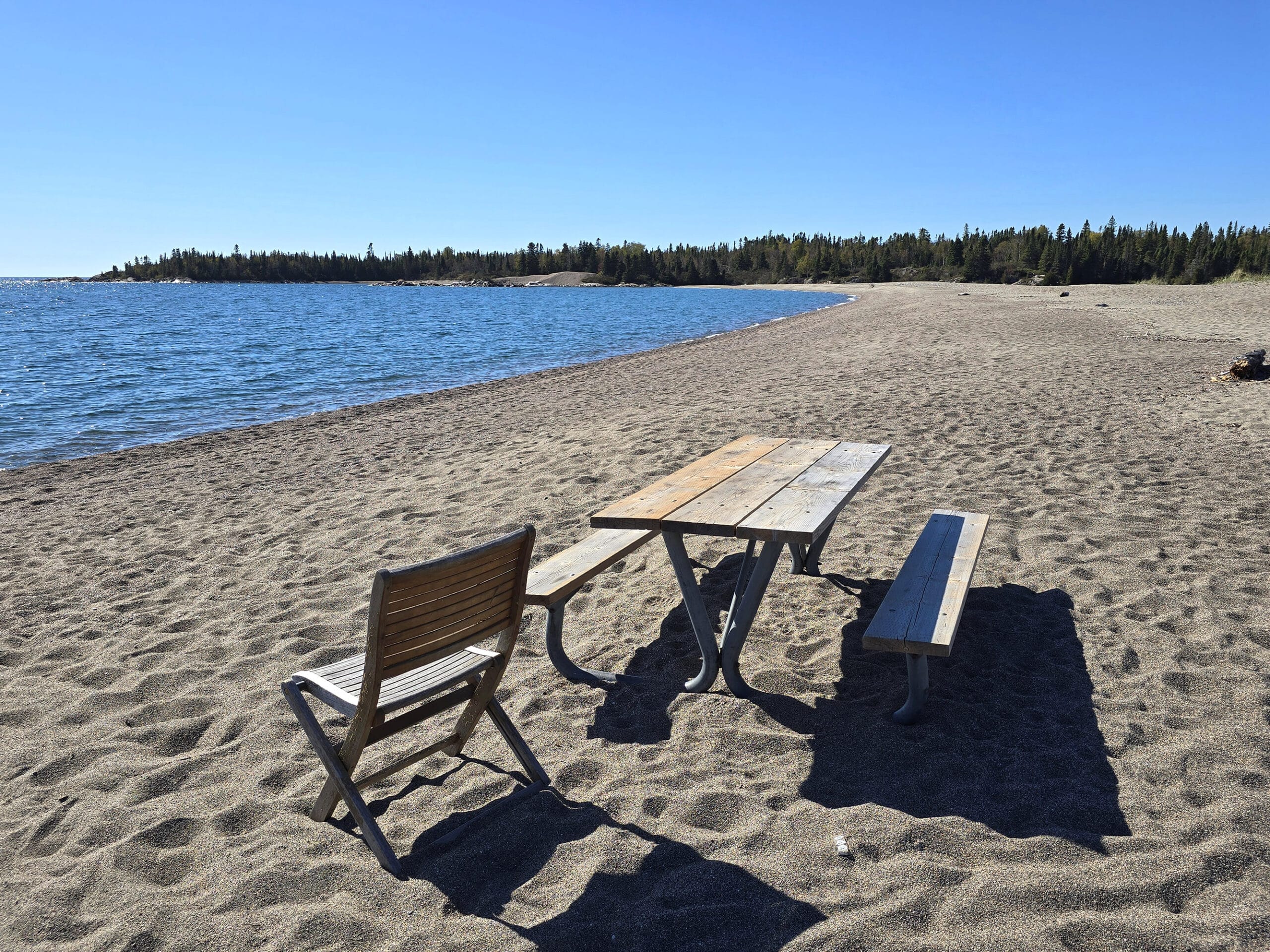 A picnic table and chair on a rocky beach.