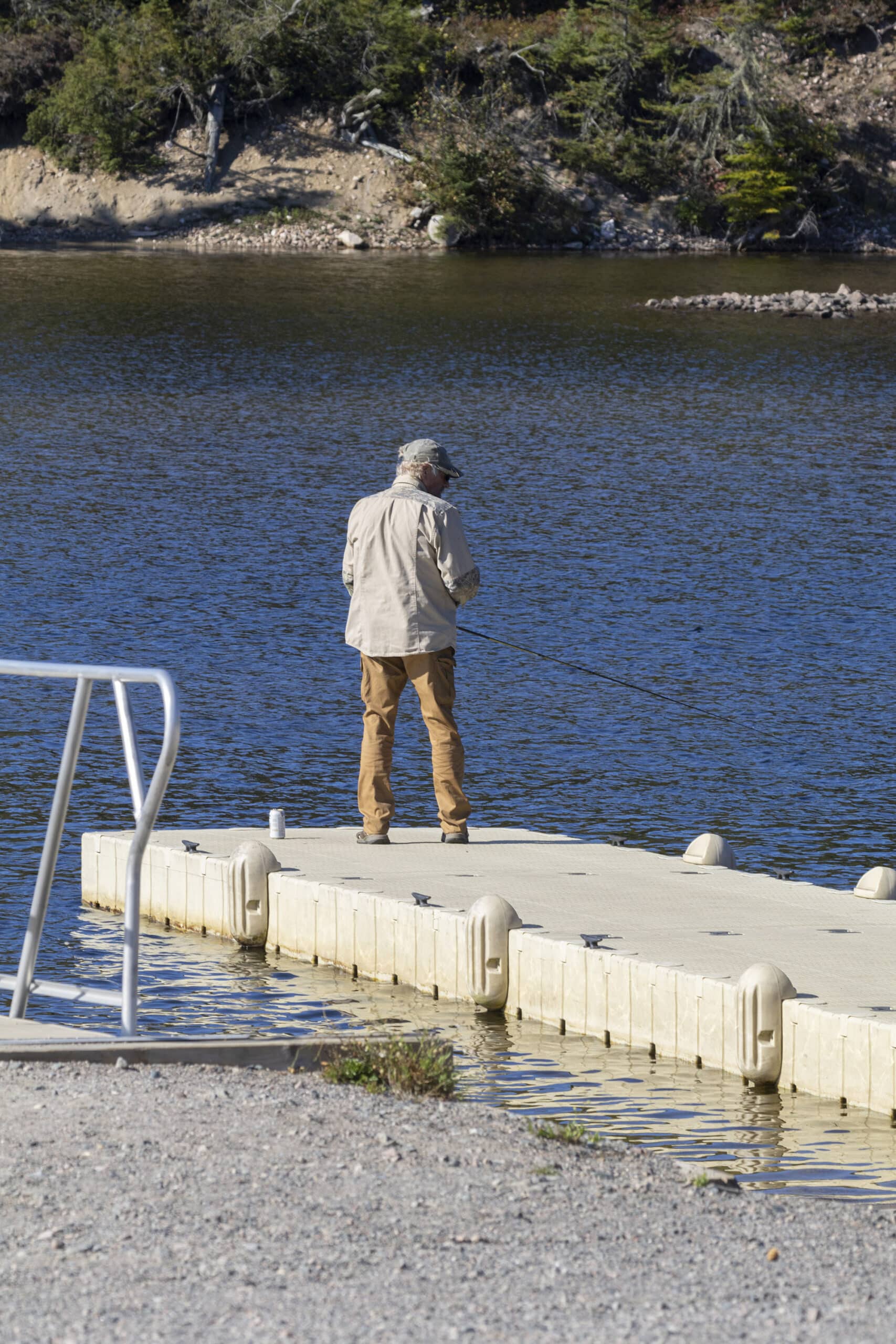 A man fishing off a floating dock at terrace bay beach.