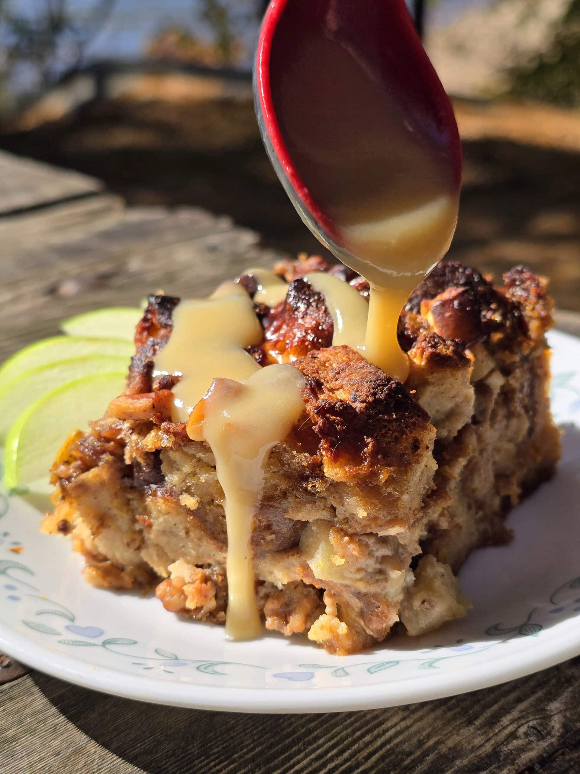 A plate of apple fritter bread pudding, drizzled with homemade maple cream sauce.