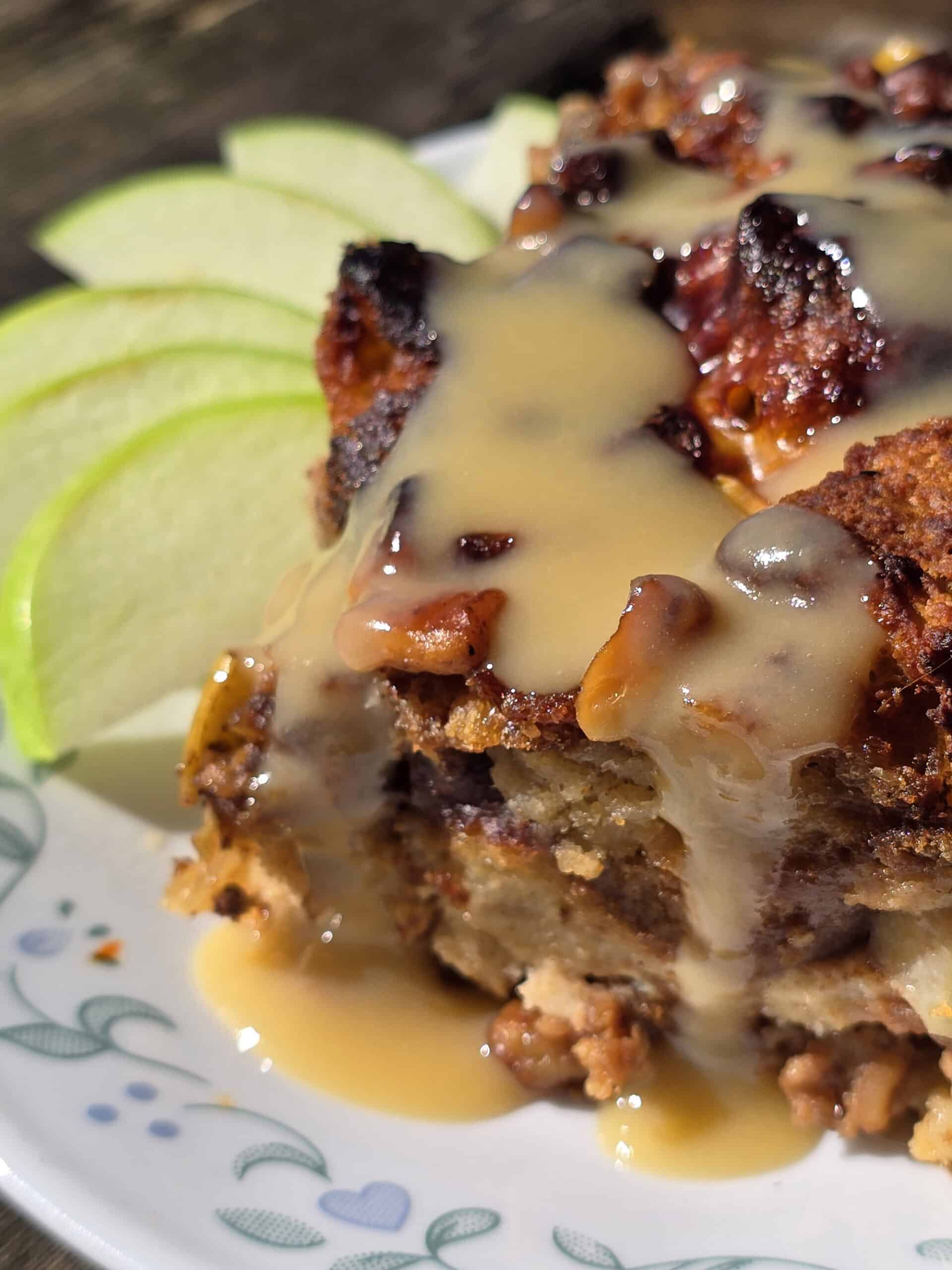 A plate of bread pudding made from apple fritters, drizzled with homemade maple cream sauce.