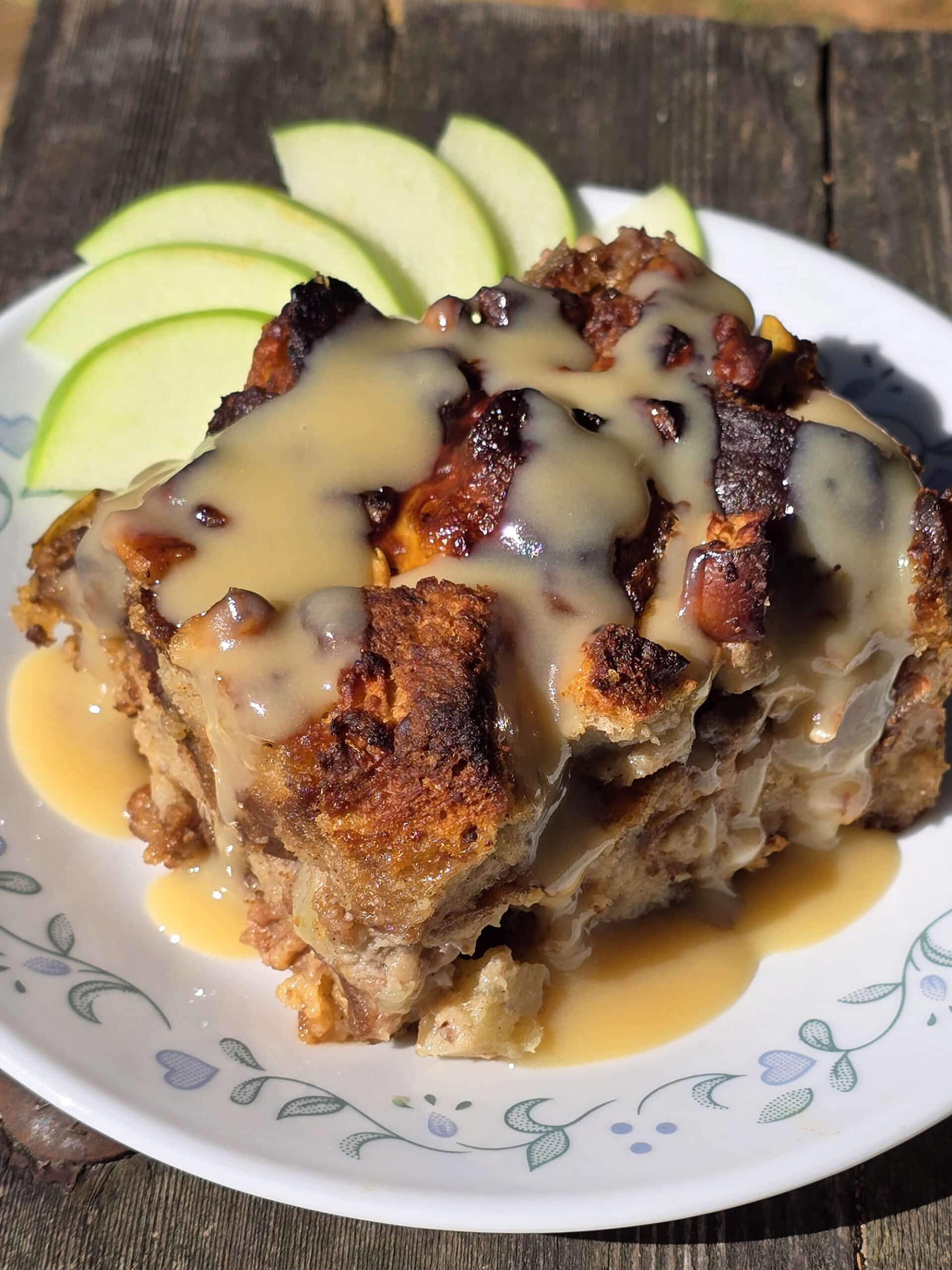 A plate of apple fritter bread pudding, drizzled with homemade maple cream sauce.