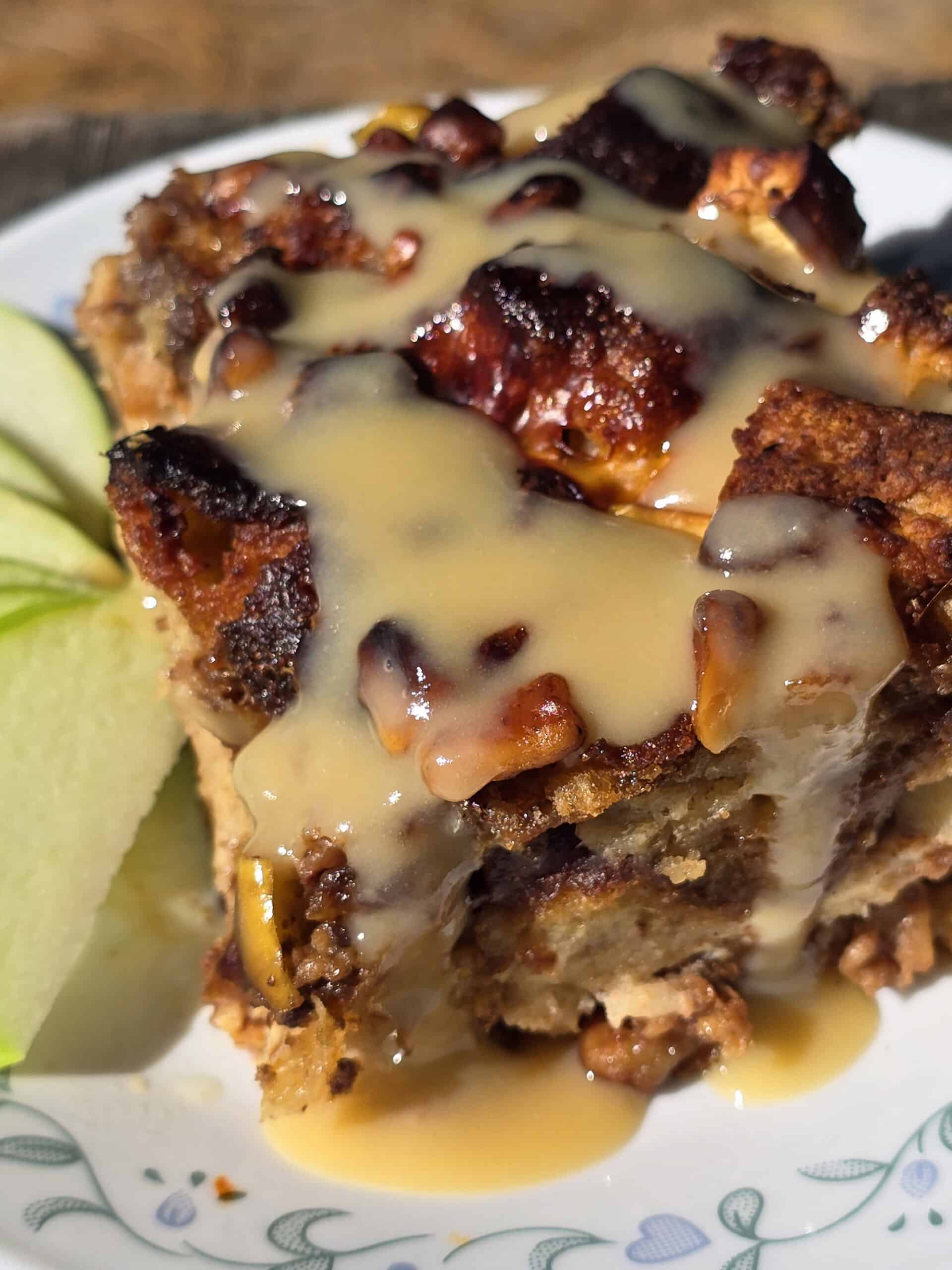 A plate of bread pudding made from apple fritters, drizzled with homemade maple cream sauce.