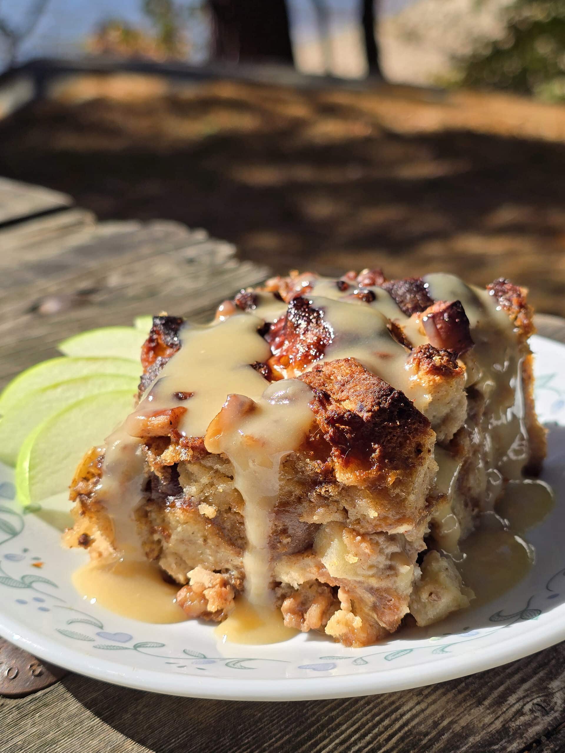 A plate of apple fritter bread pudding, drizzled with homemade maple cream sauce.