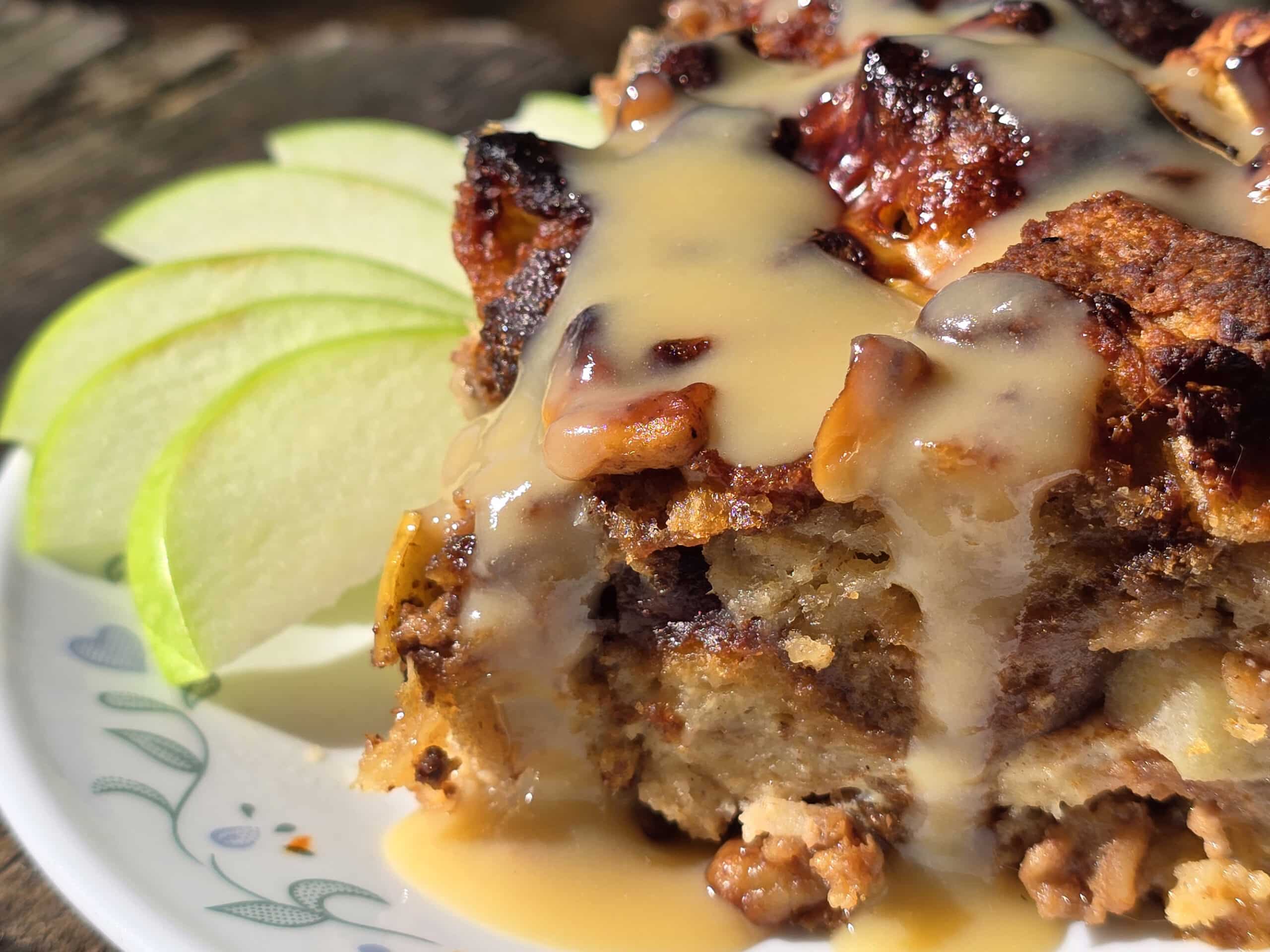 A plate of apple fritter bread pudding, drizzled with homemade maple cream sauce.