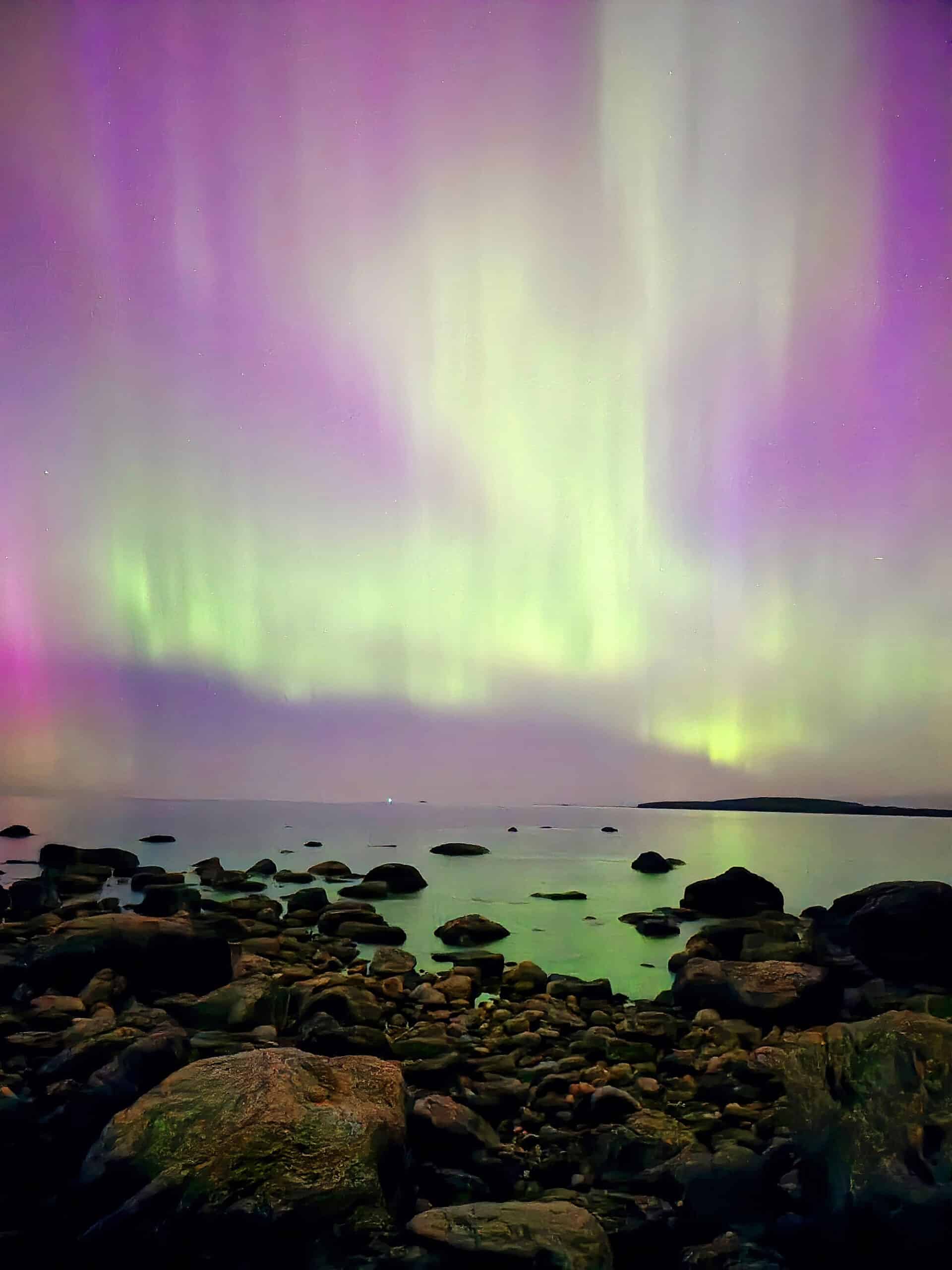 A bright pink northern lights display over georgian bay.