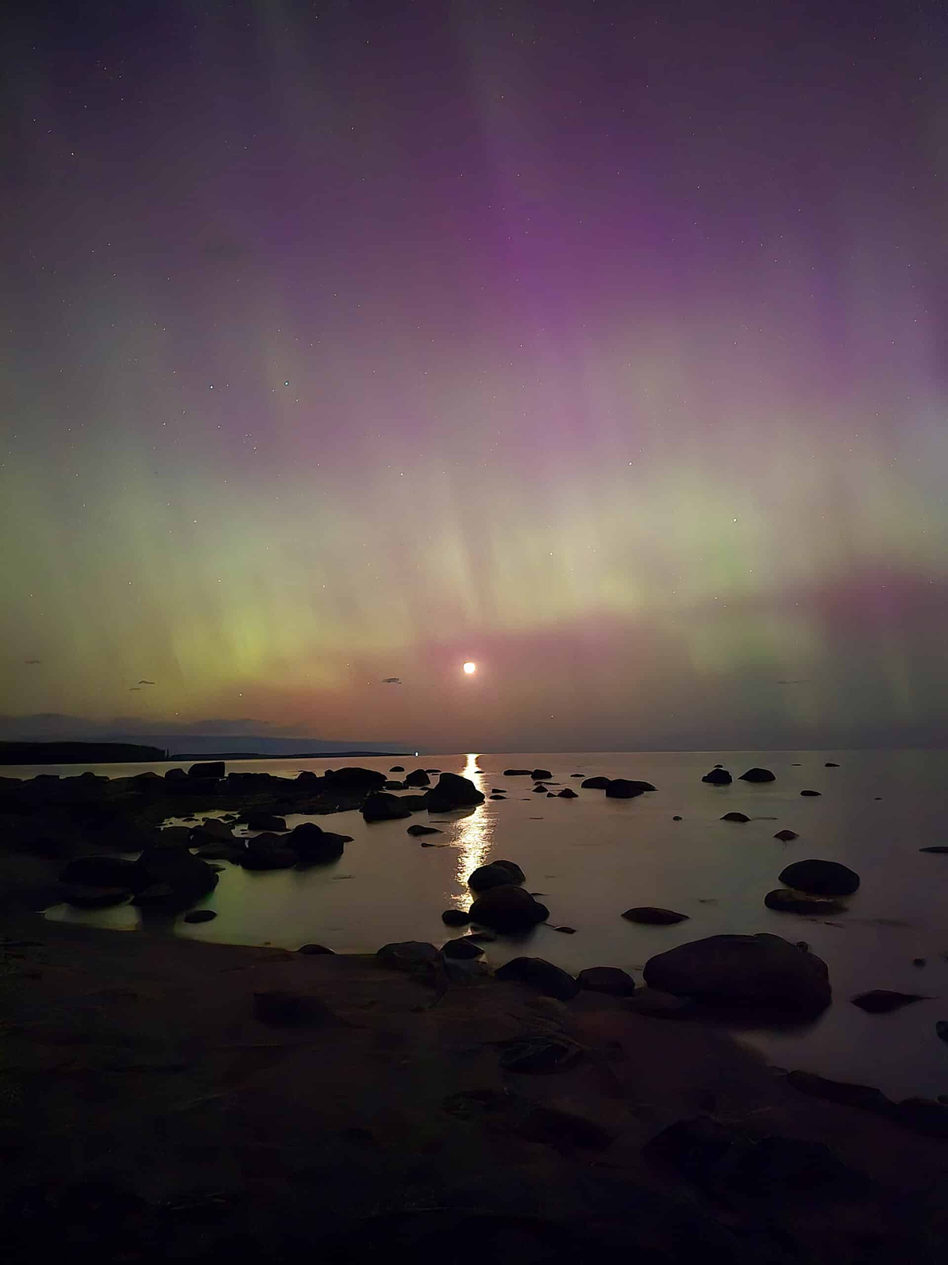 A bright purple and pink aurora borealis display over lake huron.