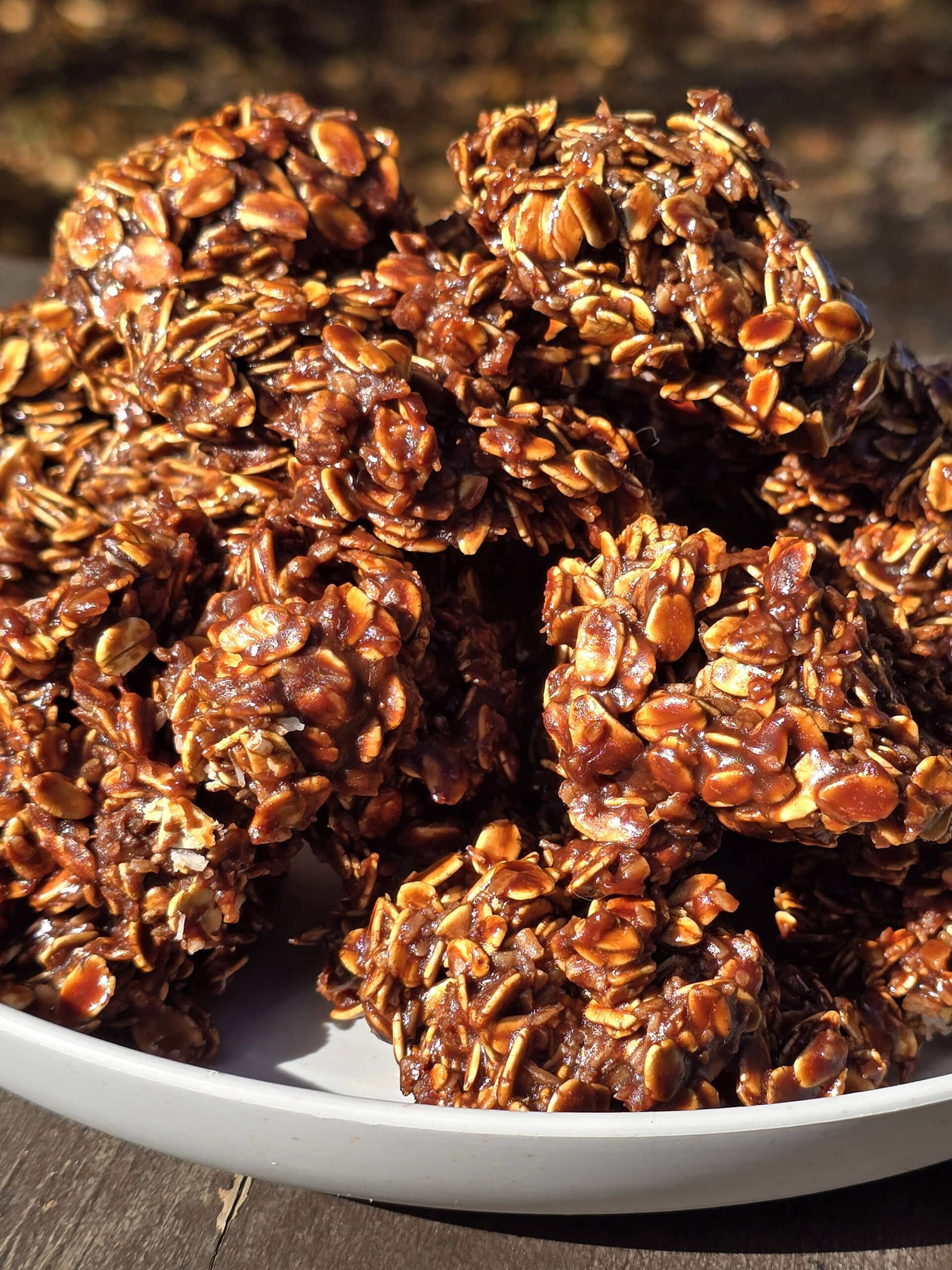 A plate of campfire haystack cookies on a picnic table, in front of a lake.