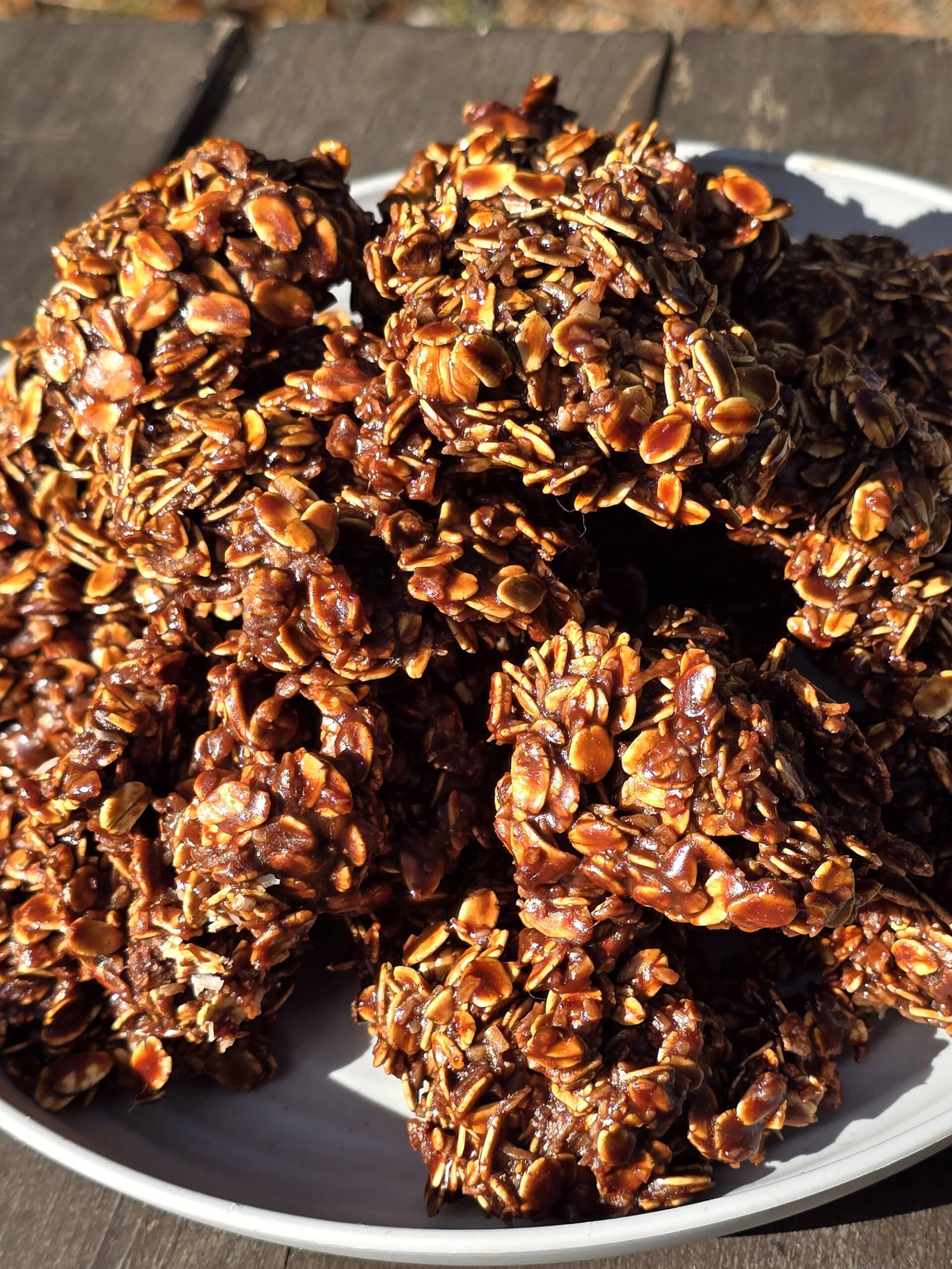 A plate of campfire haystack cookies on a picnic table, in front of a lake.