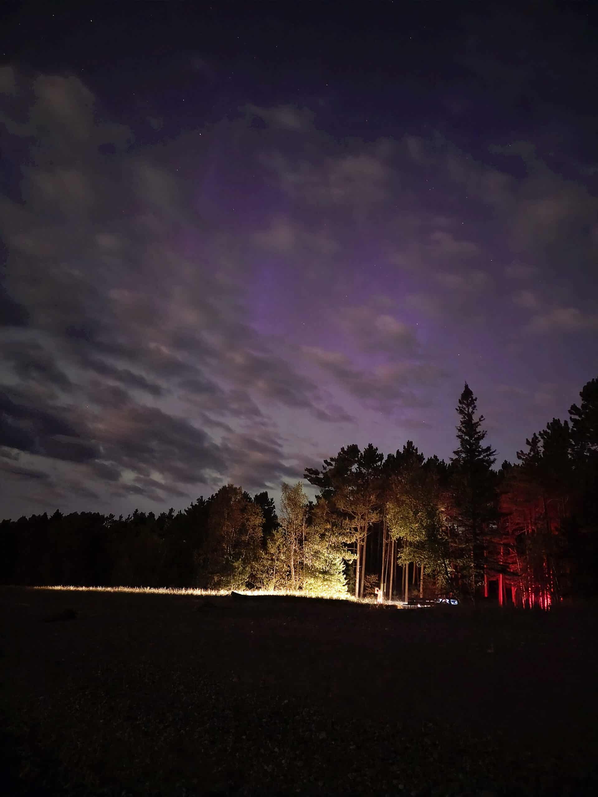 Aurora display at pancake bay provincial park, with a car driving by.