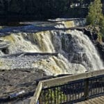 A side view of Kakabeka Falls with a boardwalk in the foreground.