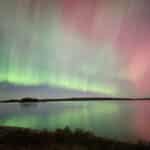 A pink and green northern lights show over a lake at Killbear Provincial Park.