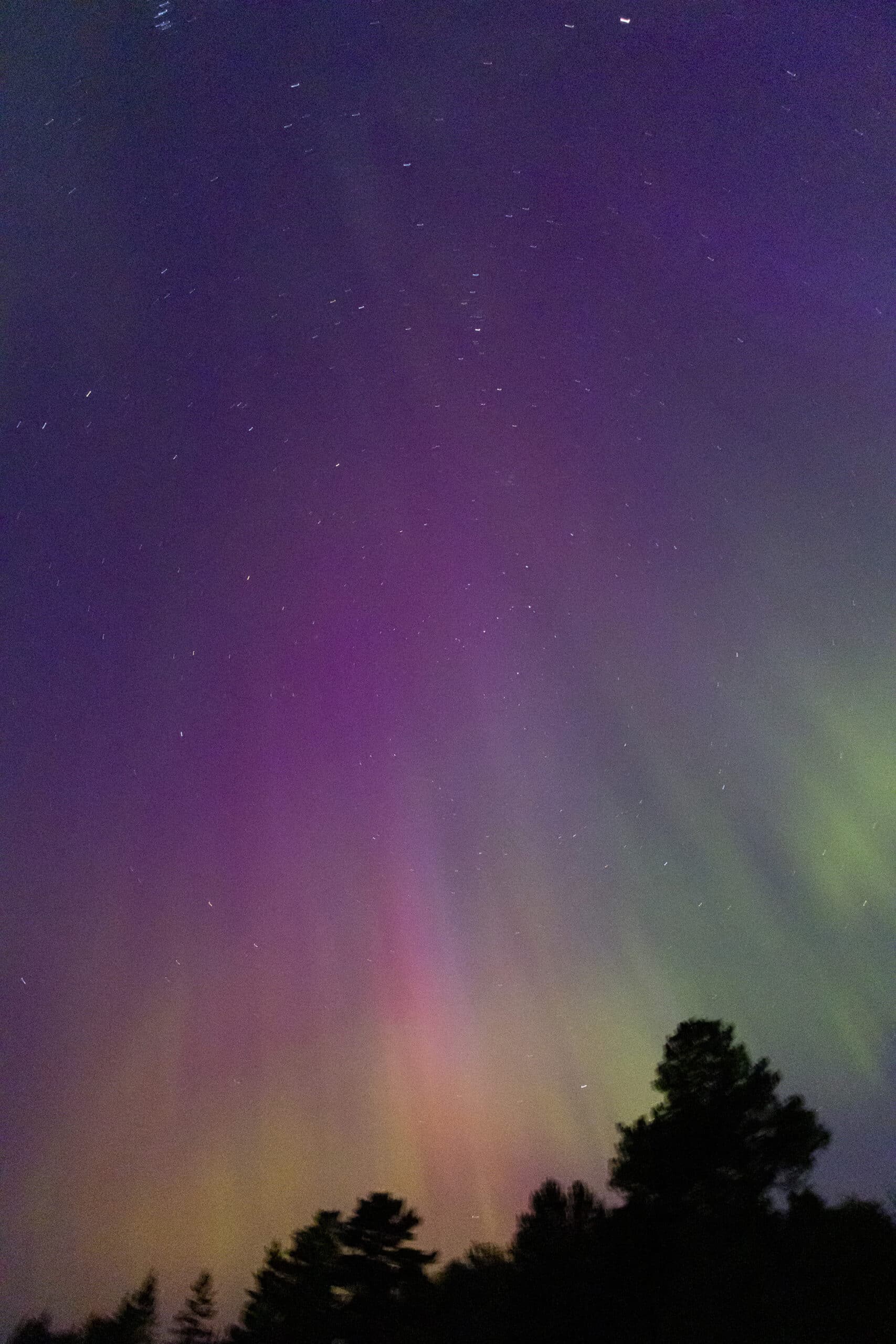 Green, orange, and purple streaks of light in the sky due to aurora borealis.