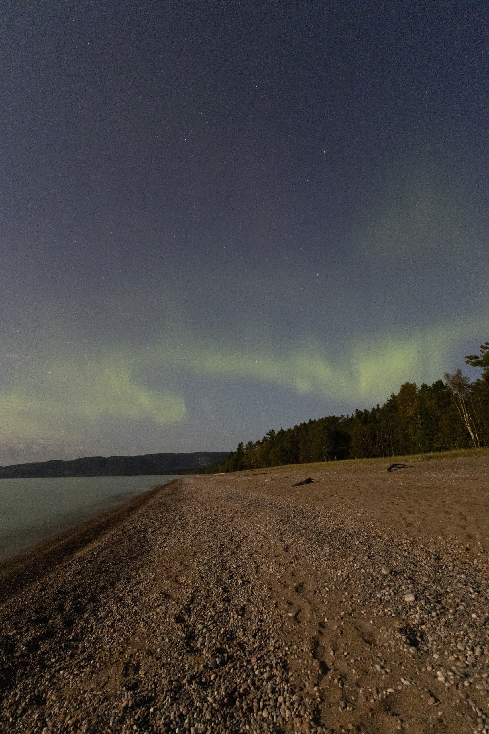 Green streaks of light in the sky over a beach, aurora borealis.