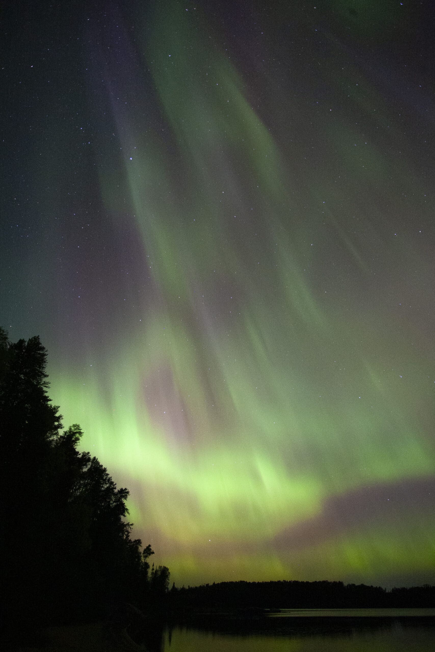 Green and red streaks of light in the sky due to aurora borealis.