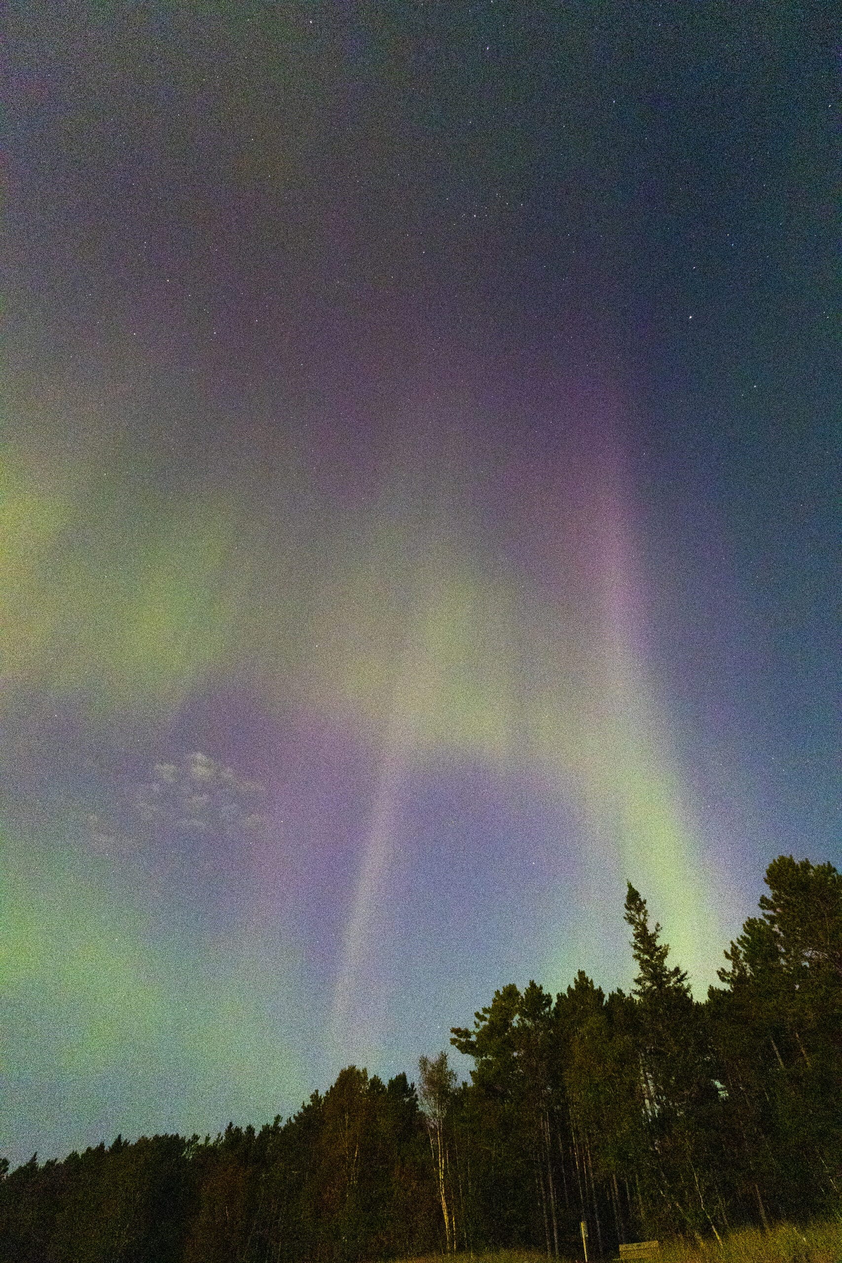 Green, orange, and purple streaks of light in the sky due to aurora borealis.