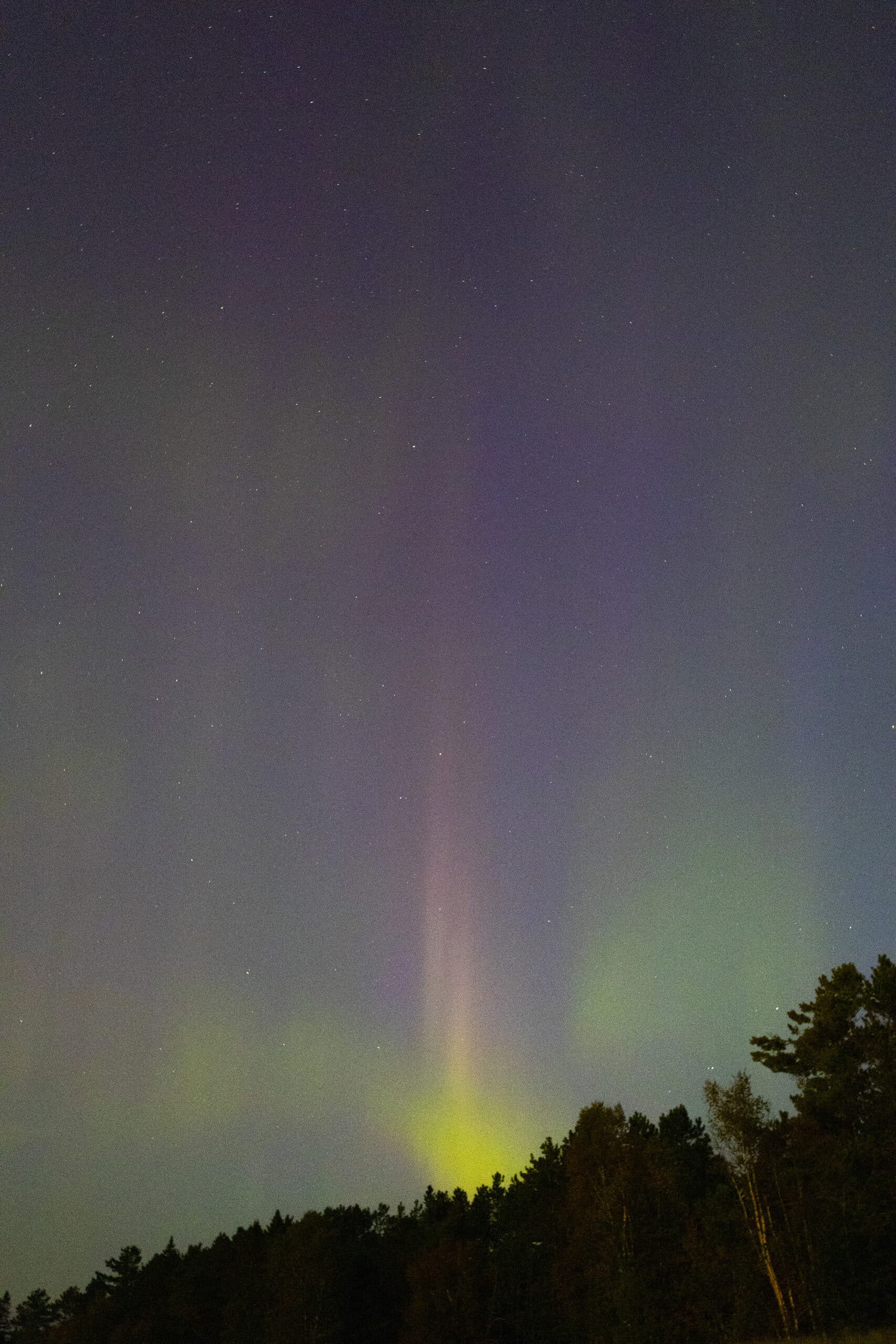 Green, orange, and purple streaks of light in the sky due to aurora borealis.