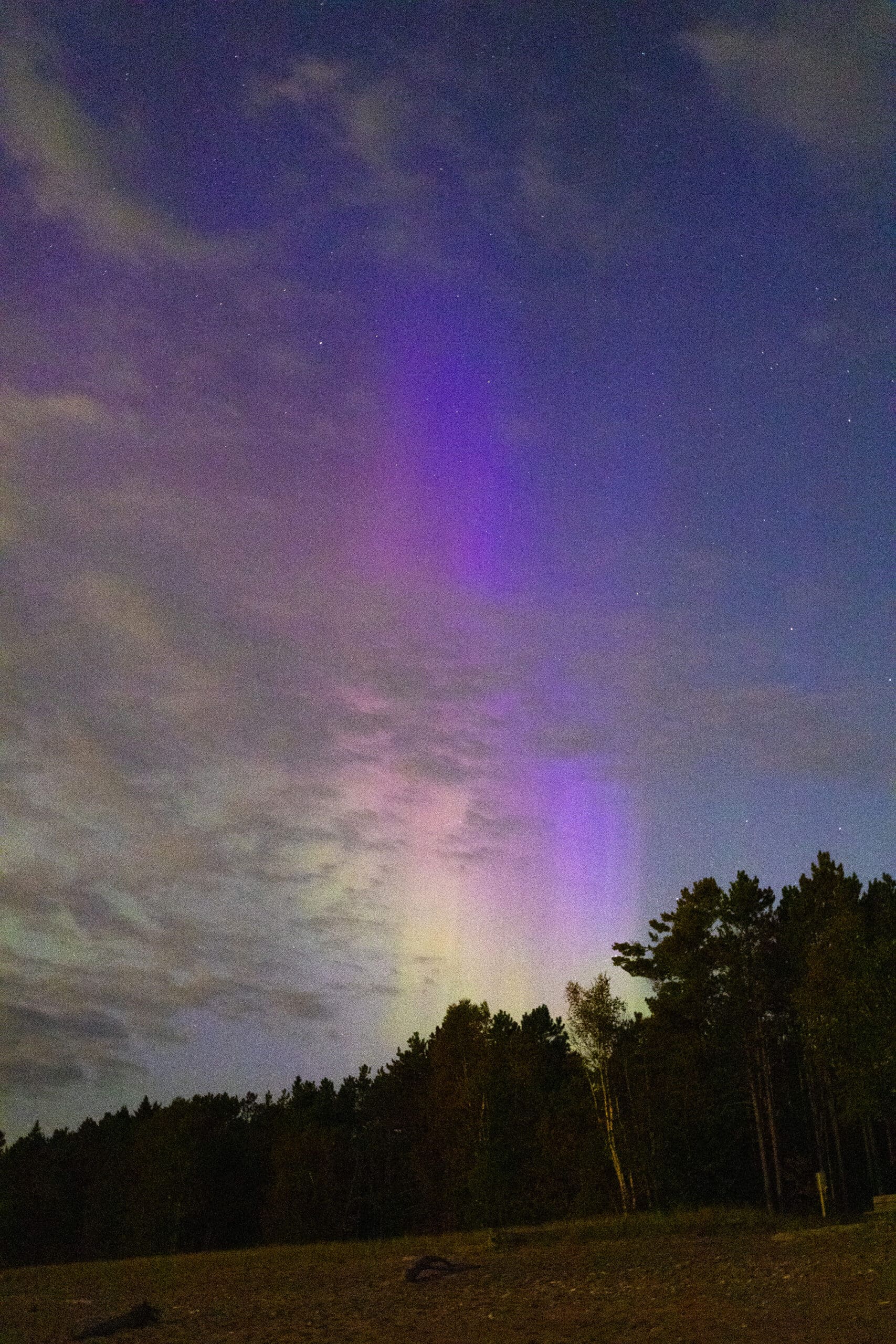 Green and purple streaks of light in the sky due to aurora borealis.