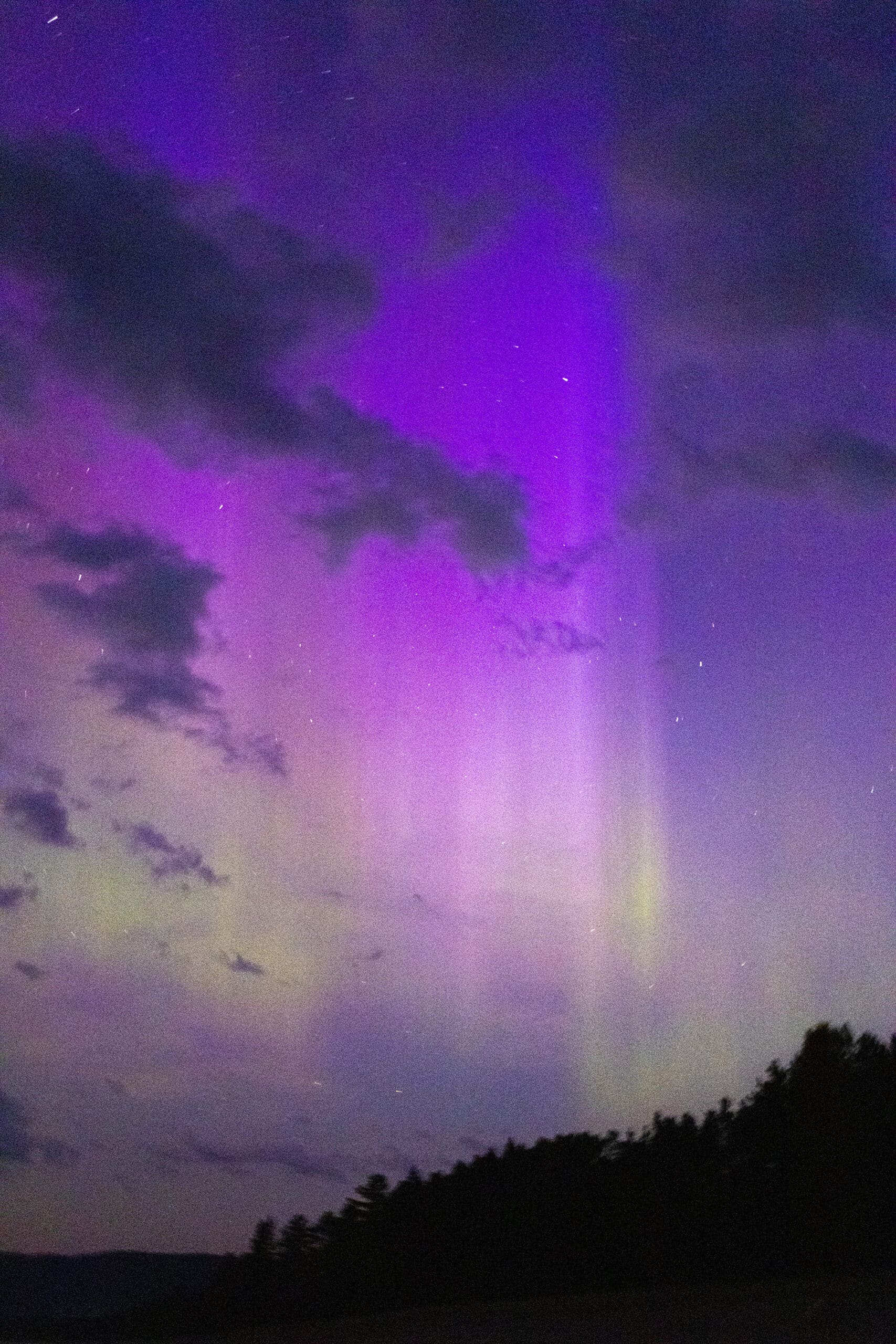 Green and purple streaks of light in the sky due to aurora borealis.