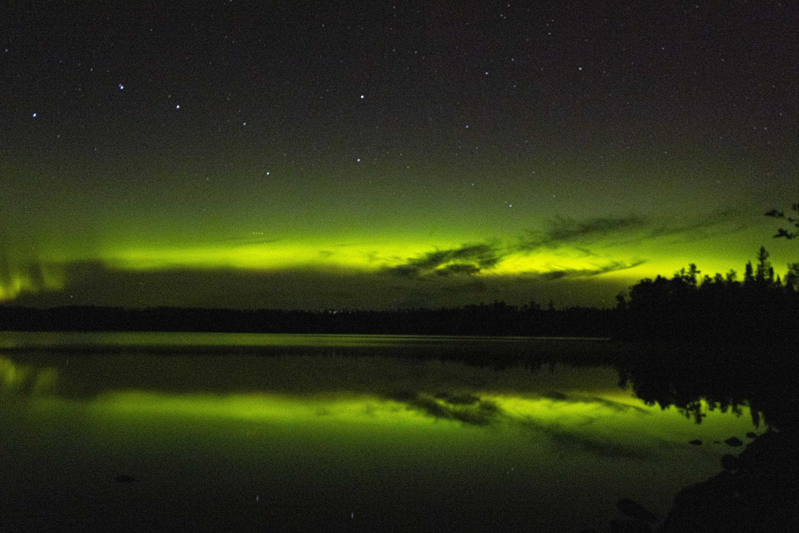 Green streaks of light in the sky due to aurora borealis.