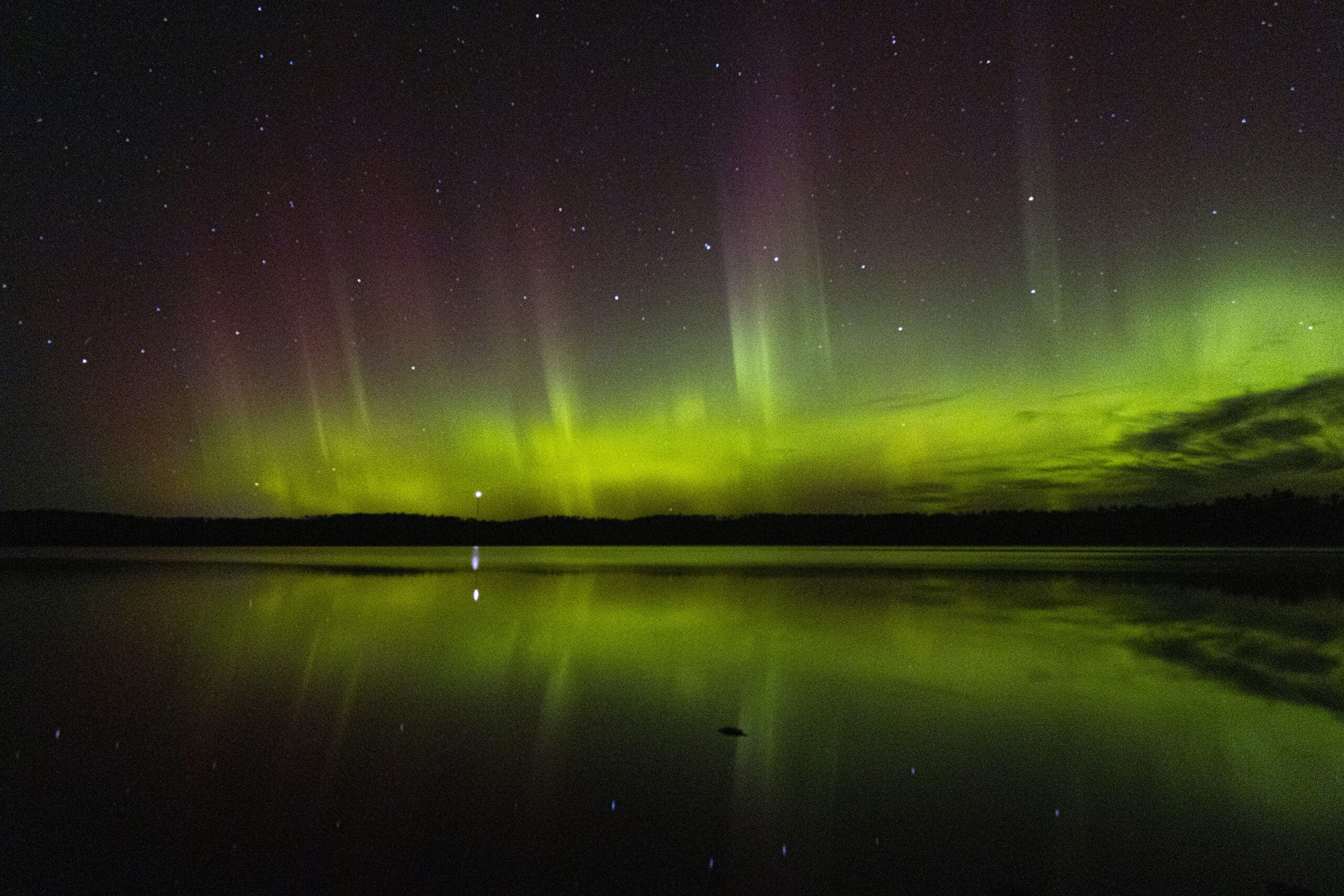 Green and red streaks of light in the sky due to aurora borealis.