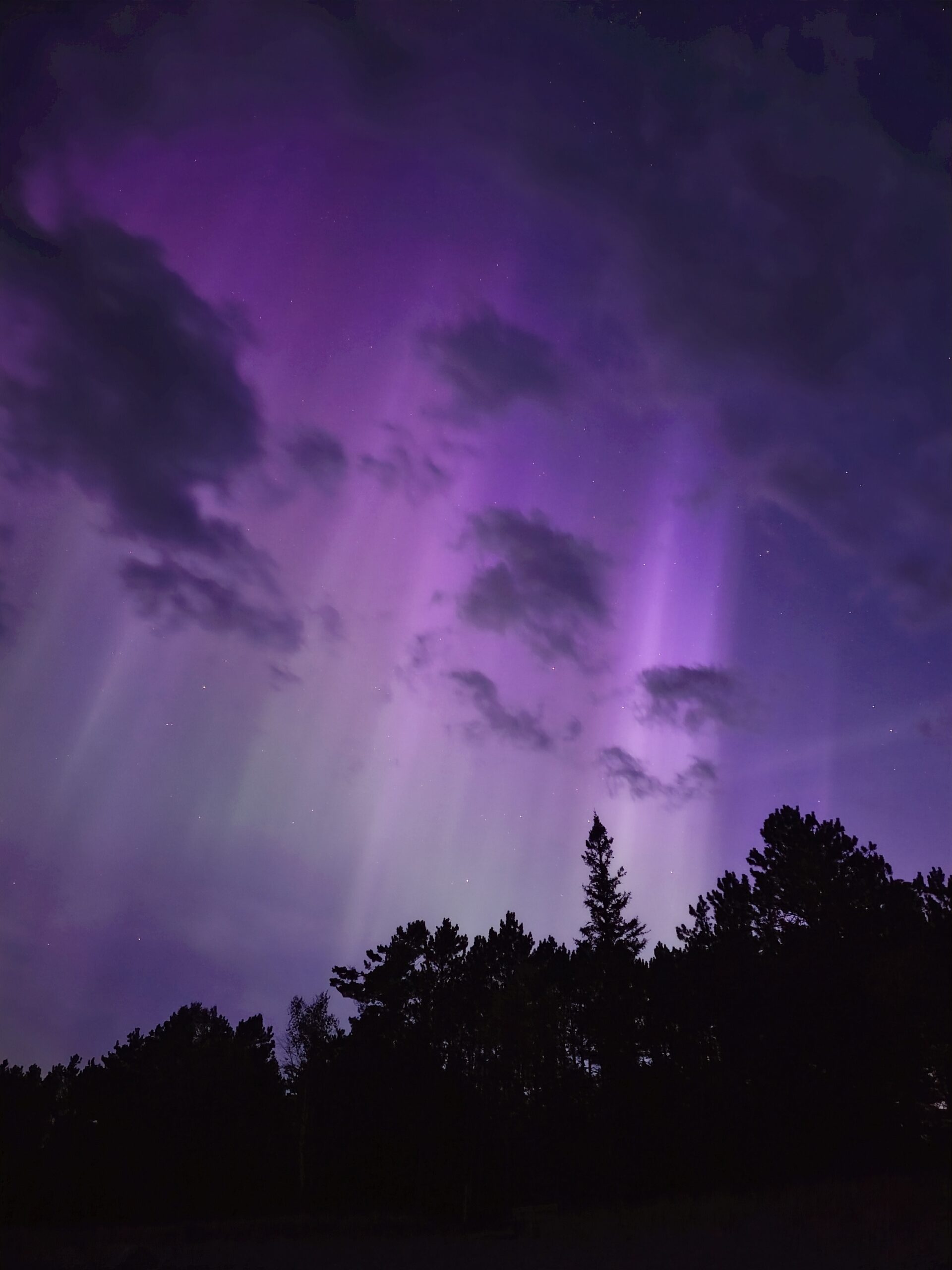 Green and purple streaks of light in the sky due to aurora borealis.