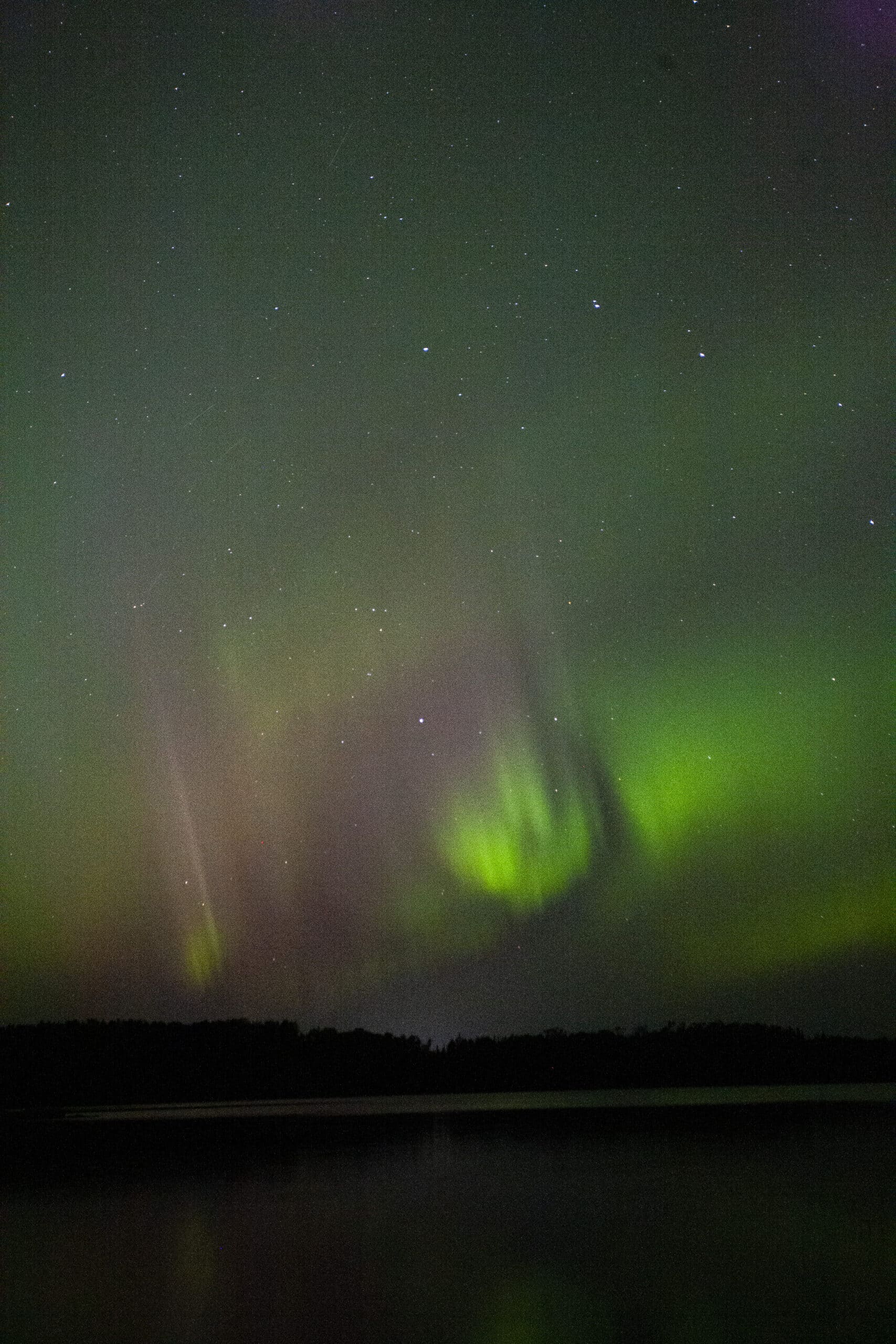 Green and red streaks of light in the sky due to aurora borealis.