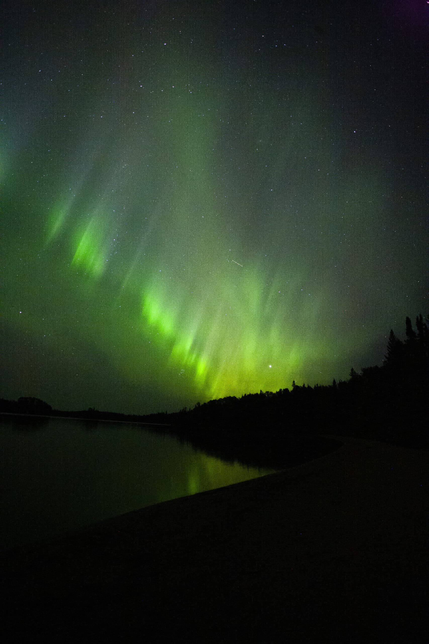 Green and red streaks of light in the sky due to aurora borealis.