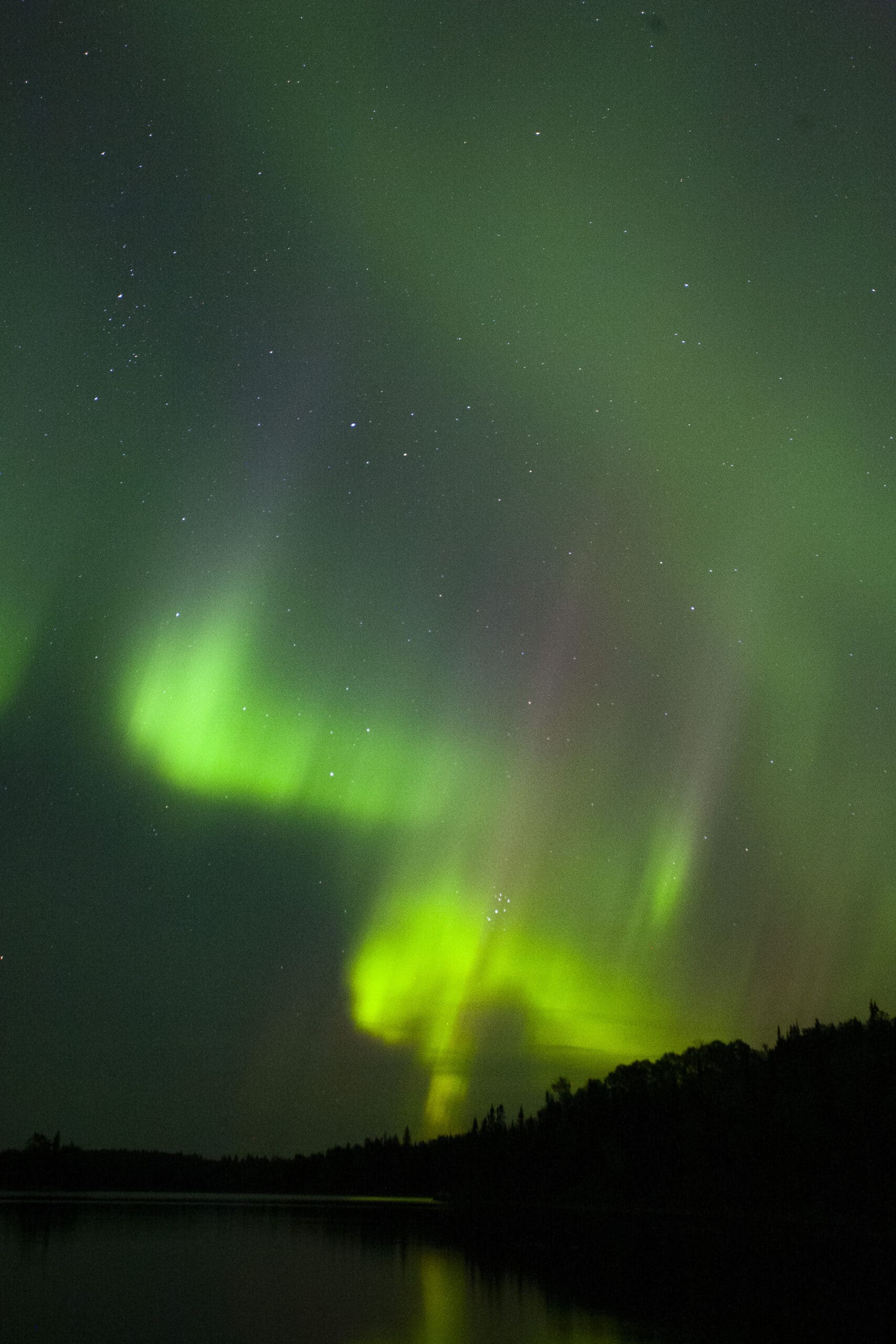 Green and red streaks of light in the sky due to aurora borealis.