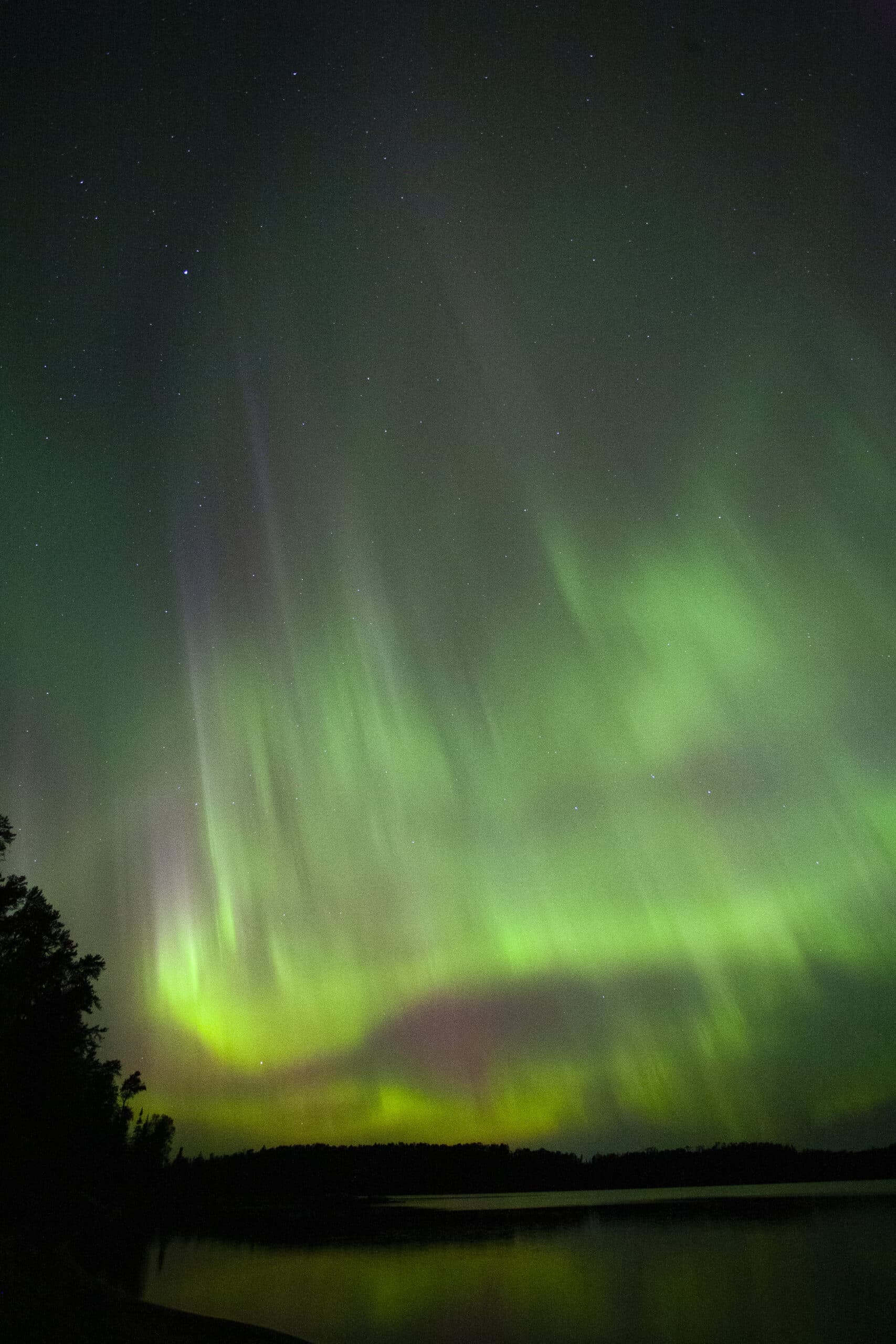 Green and red streaks of light in the sky due to aurora borealis.