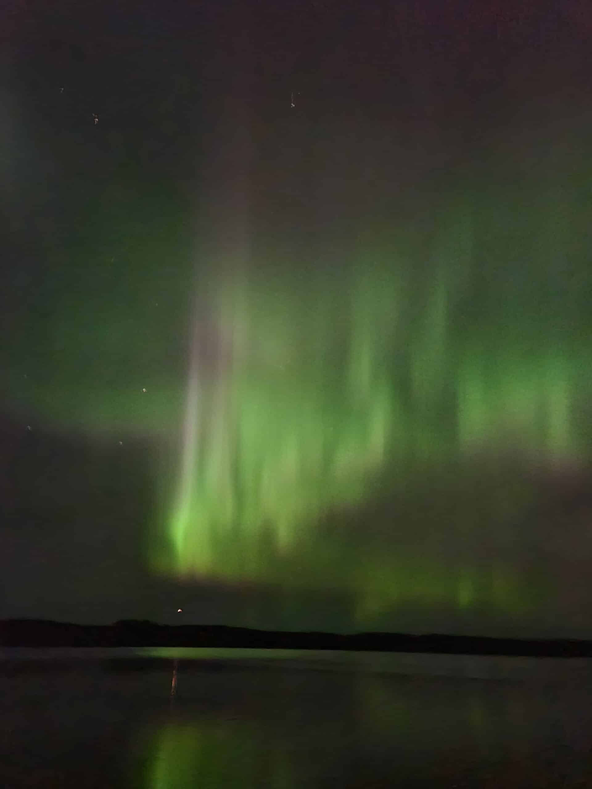 Green and red streaks of light in the sky due to aurora borealis.