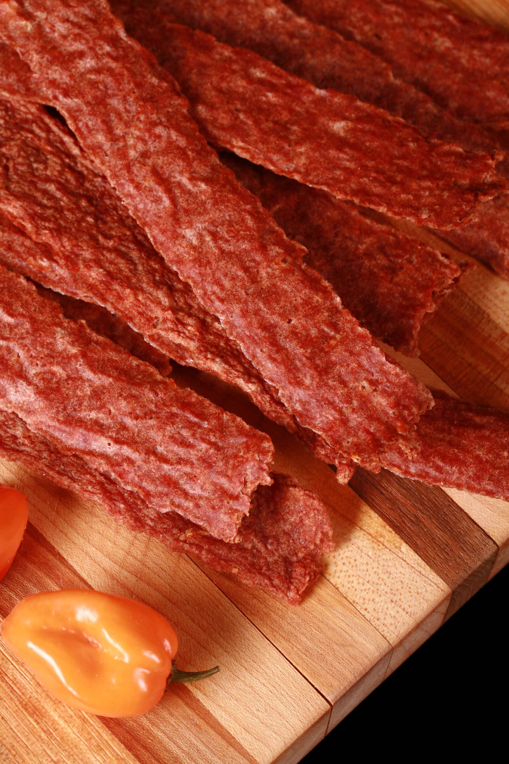 A pile of mango habanero chicken jerky on a cutting board.